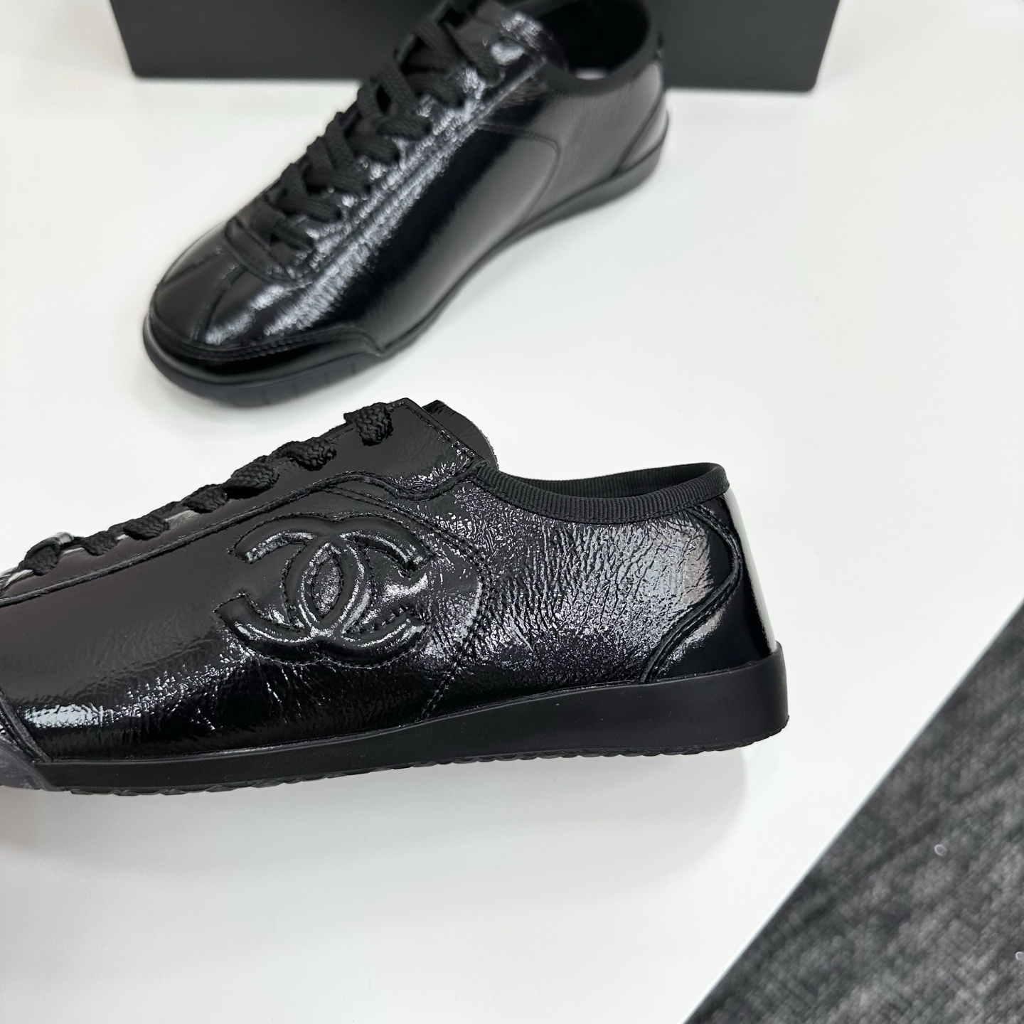 Luxury Chanel low-top sneakers in shiny black patent leather featuring an embossed CC logo on the side - Hình 8