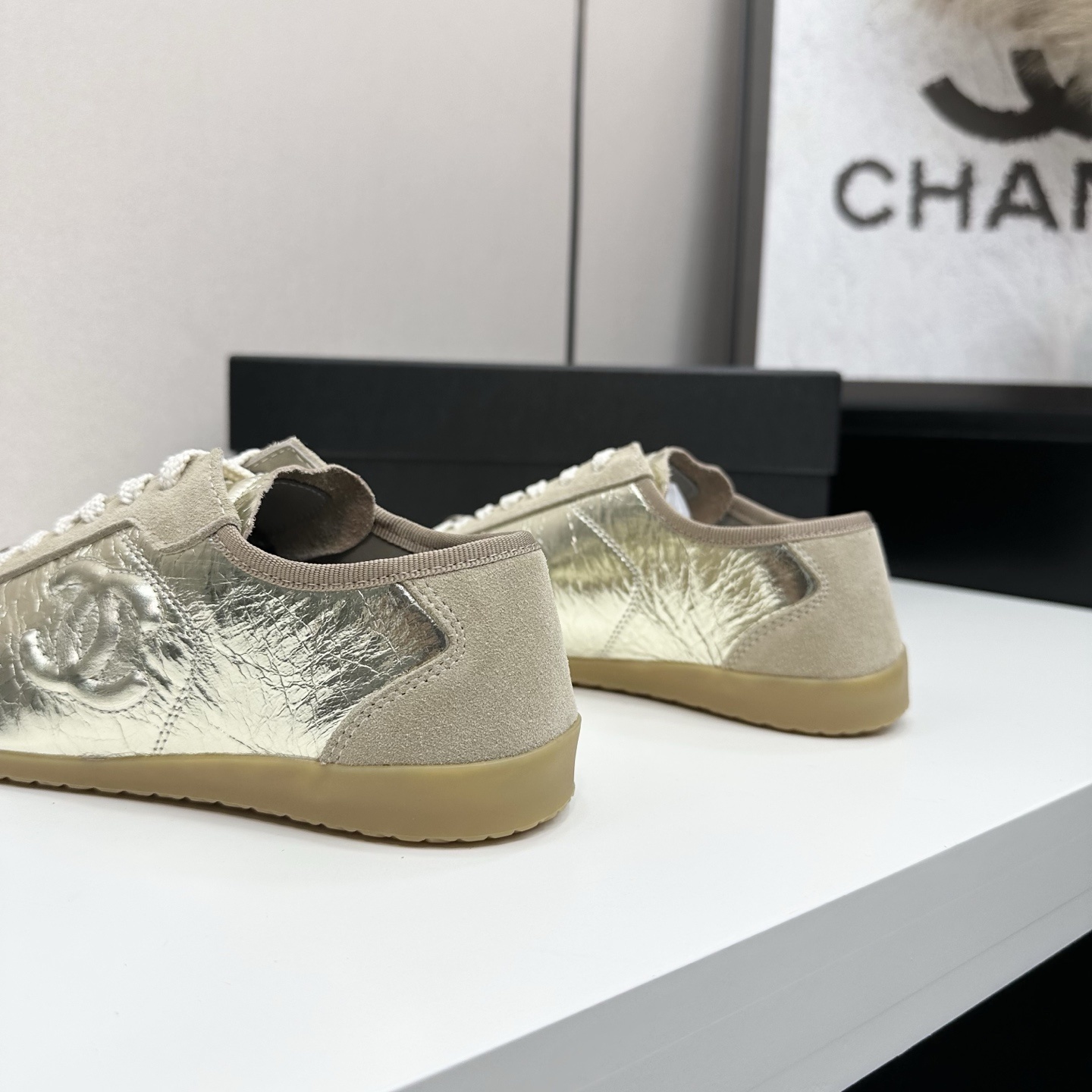 Chanel low-top sneakers featuring metallic gold crinkled leather, beige suede accents, and gum rubber soles displayed on a black box. - Hình 7
