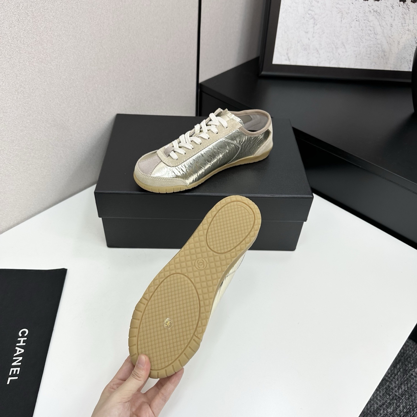 Chanel low-top sneakers featuring metallic gold crinkled leather, beige suede accents, and gum rubber soles displayed on a black box. - Hình 4
