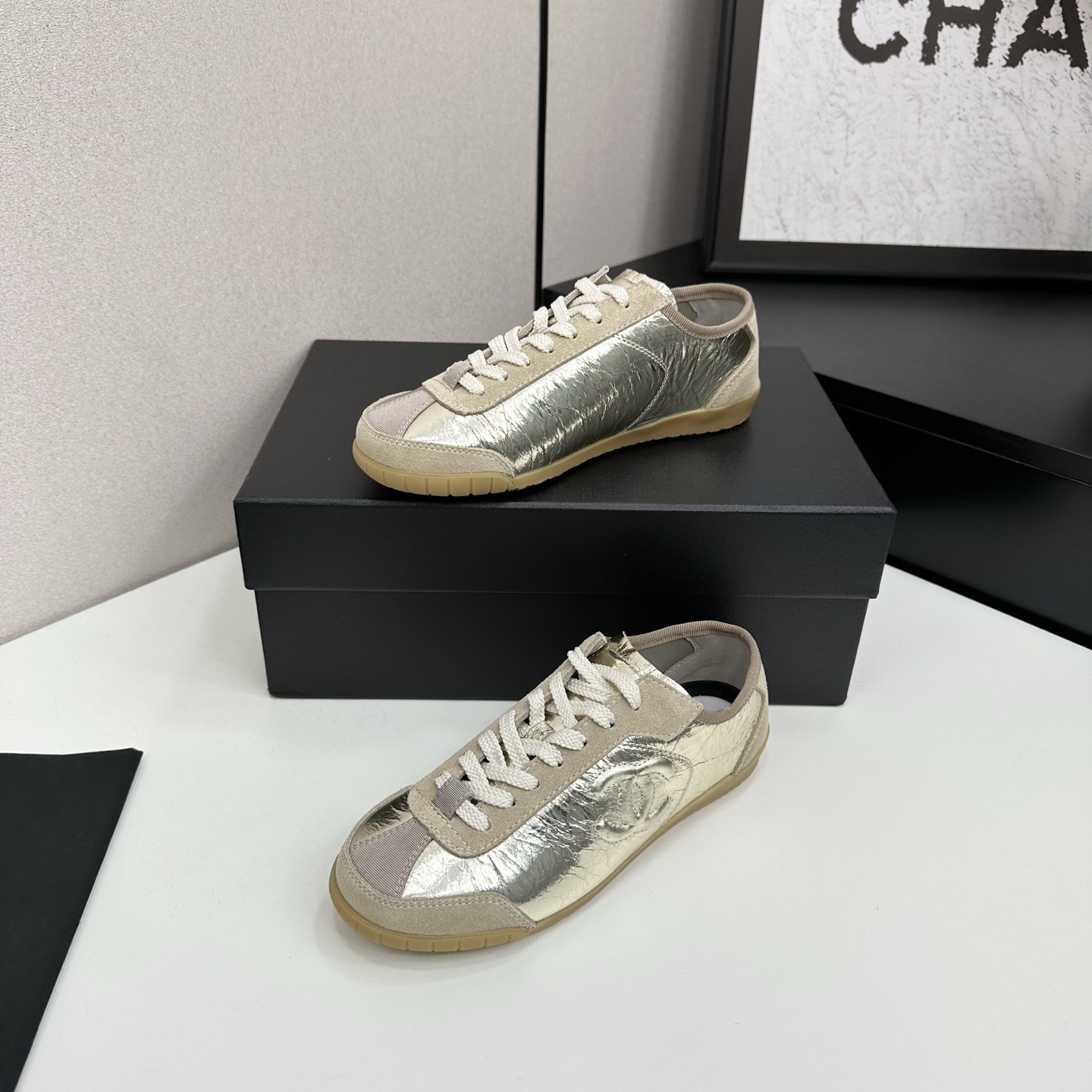 Chanel low-top sneakers featuring metallic gold crinkled leather, beige suede accents, and gum rubber soles displayed on a black box. - Hình 2