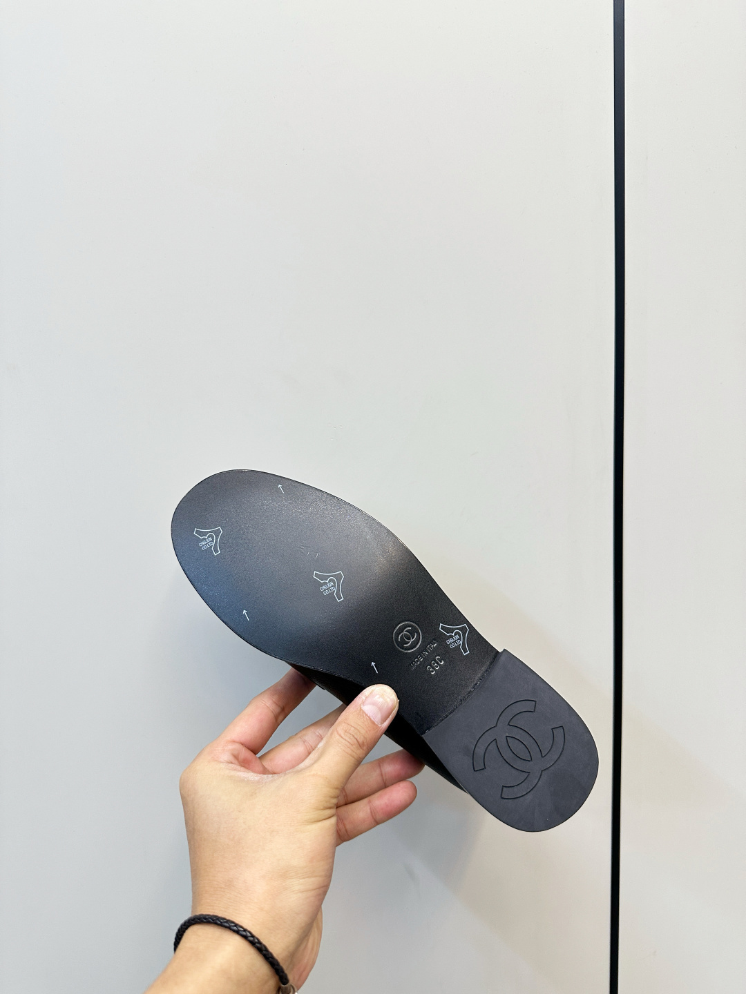 A pair of black Chanel leather loafers with silver crystal logo embellishment displayed on a black box. - Hình 9