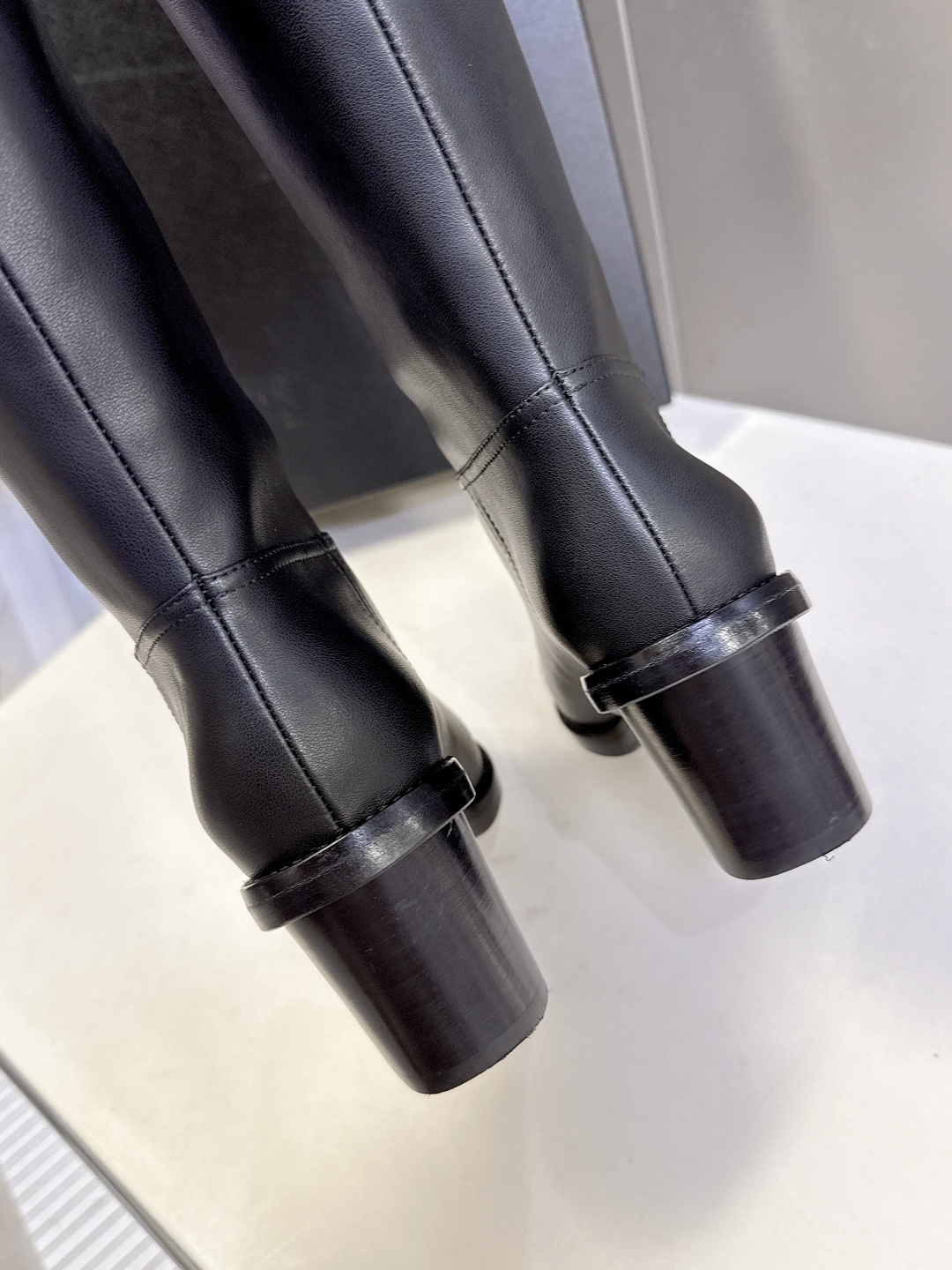 Pair of Chanel black leather knee-high boots with CC logo and block heel next to a Chanel shoe box - Hình 8