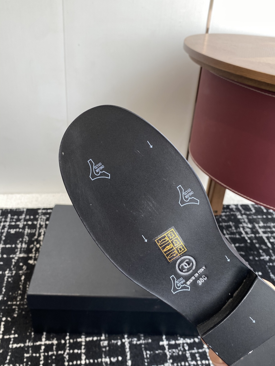 A pair of luxury Chanel black quilted leather knee-high riding boots placed on a black designer box. - Hình 9