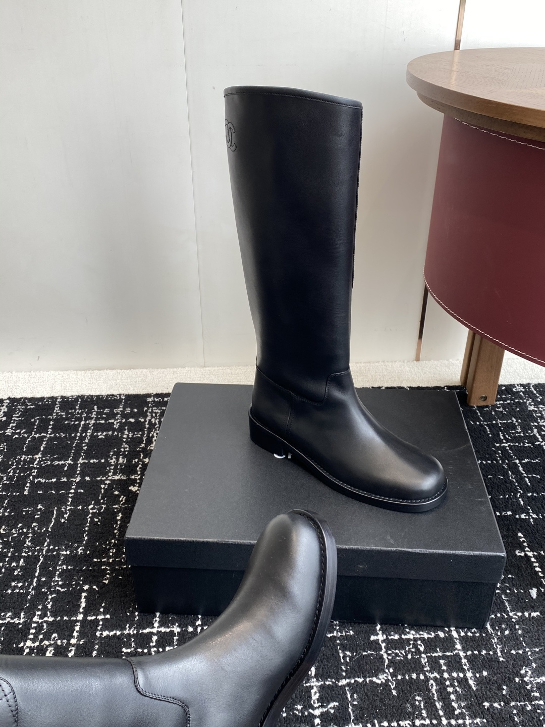 A pair of luxury Chanel black quilted leather knee-high riding boots placed on a black designer box. - Hình 7