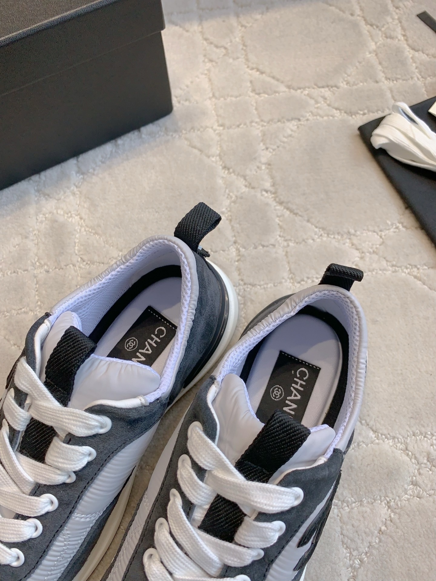 A pair of grey and black Chanel sneakers with white laces and CC logo, shown with original box and accessories. - Hình 6