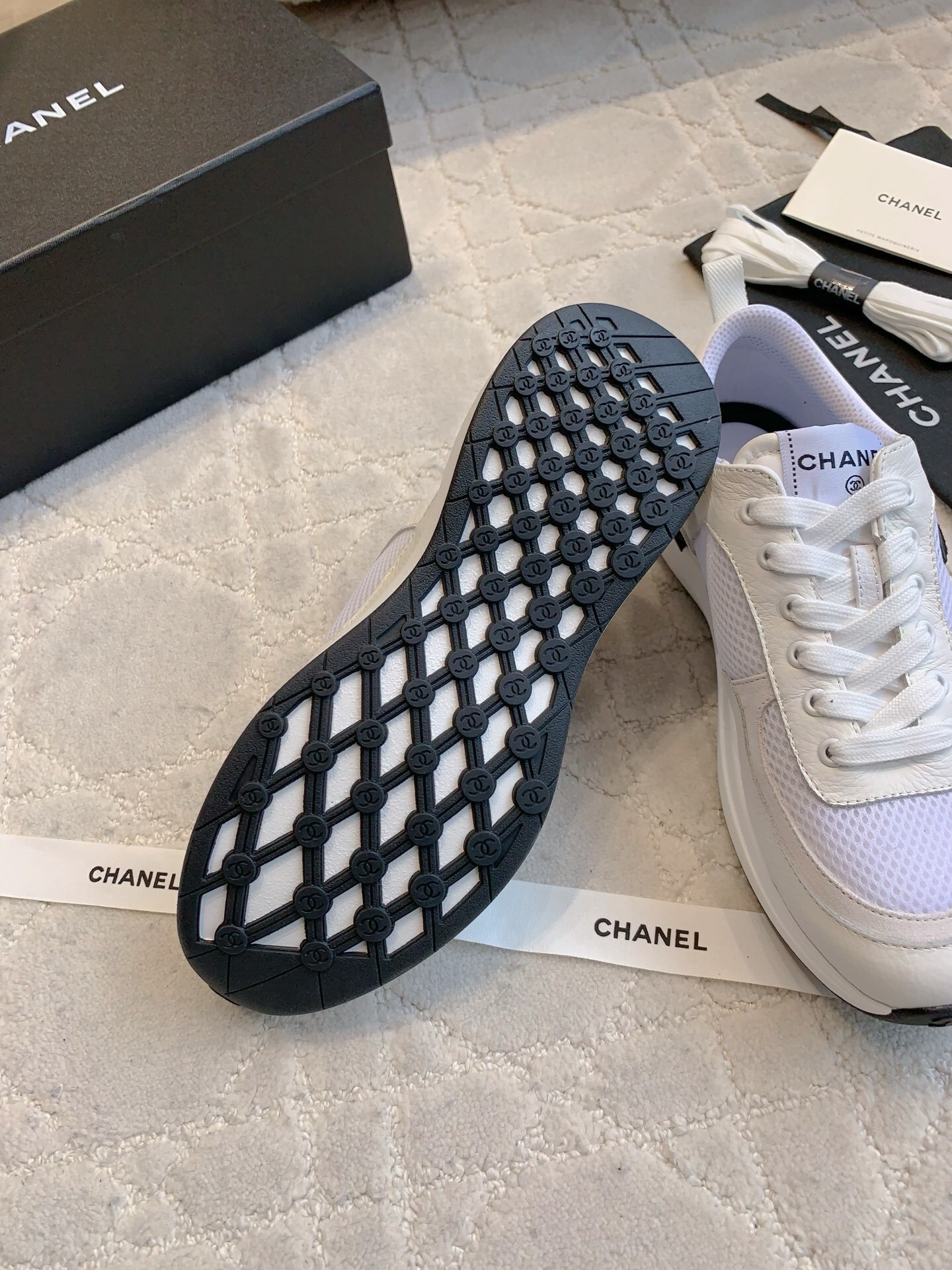 Pair of Chanel white leather and mesh sneakers with black CC logo displayed with original box and accessories. - Hình 9