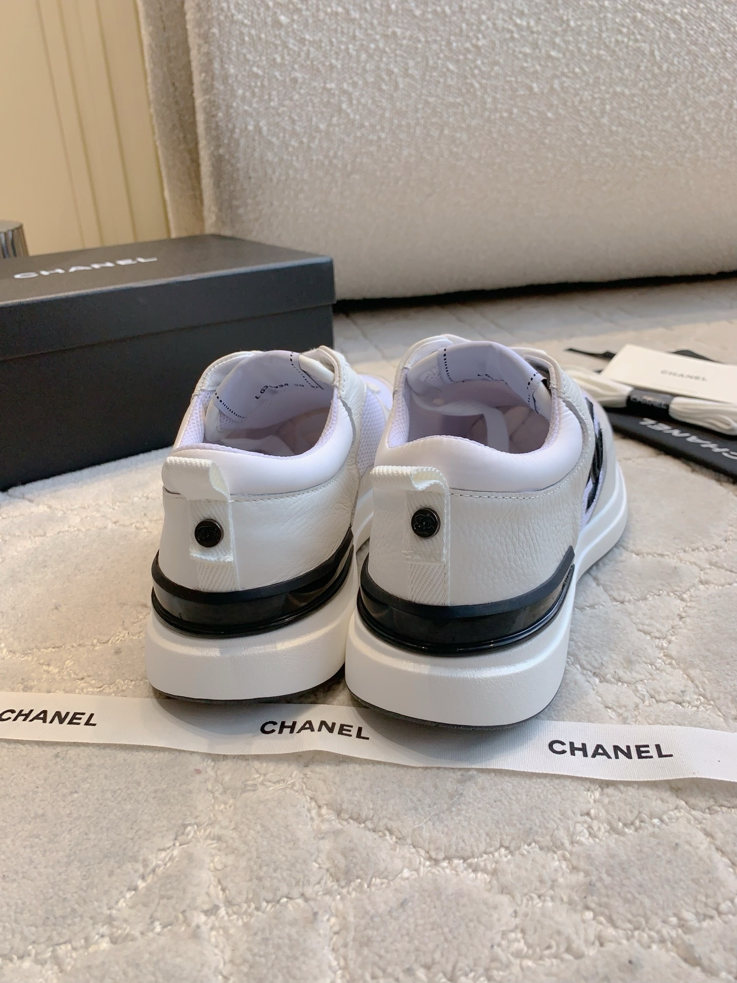 Pair of Chanel white leather and mesh sneakers with black CC logo displayed with original box and accessories. - Hình 8