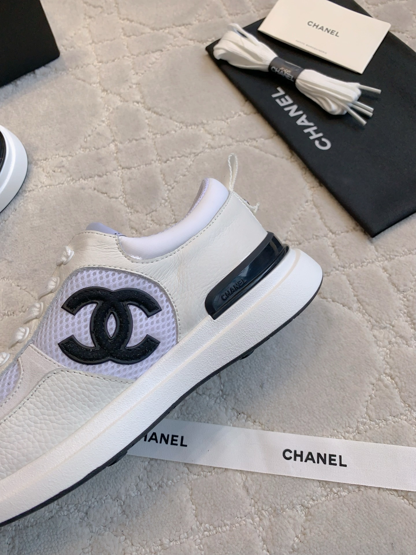 Pair of Chanel white leather and mesh sneakers with black CC logo displayed with original box and accessories. - Hình 7