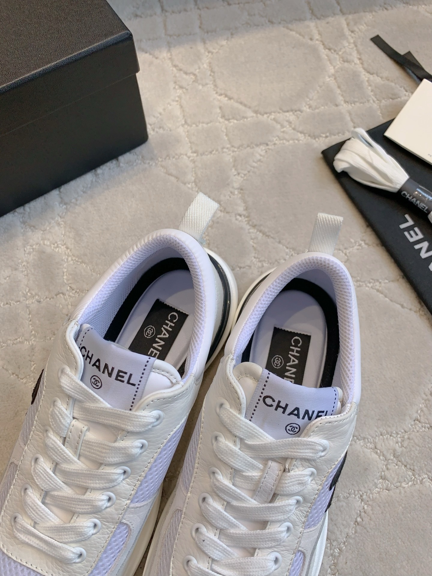 Pair of Chanel white leather and mesh sneakers with black CC logo displayed with original box and accessories. - Hình 6