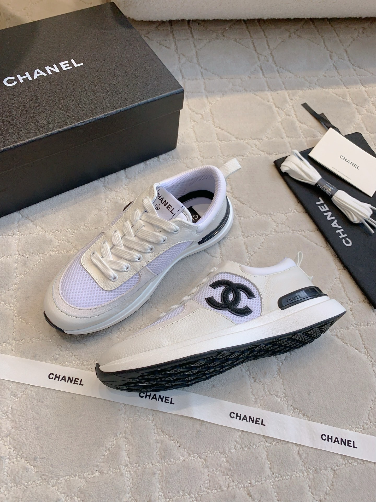 Pair of Chanel white leather and mesh sneakers with black CC logo displayed with original box and accessories. - Hình 4
