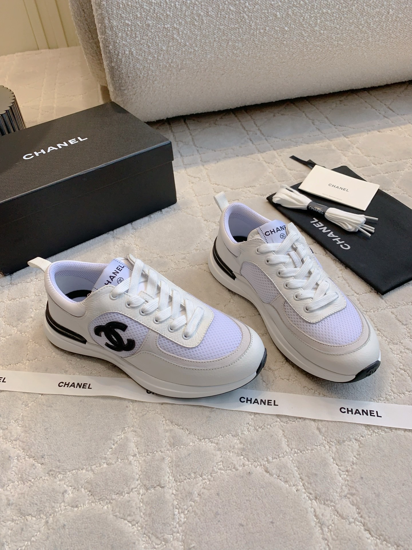 Pair of Chanel white leather and mesh sneakers with black CC logo displayed with original box and accessories. - Hình 3