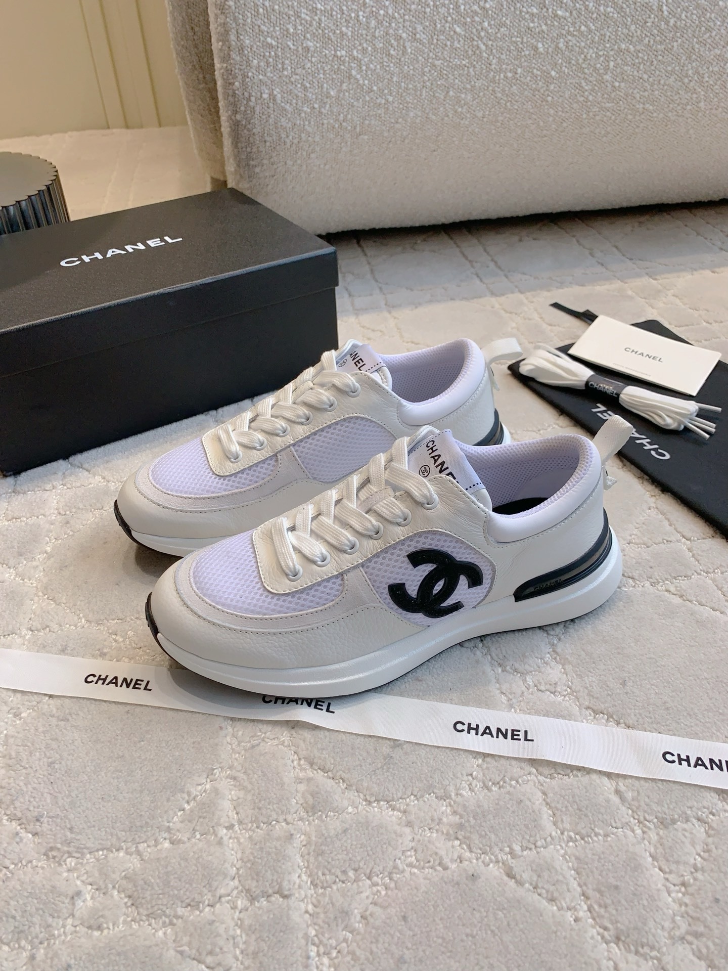 Pair of Chanel white leather and mesh sneakers with black CC logo displayed with original box and accessories. - Hình 2