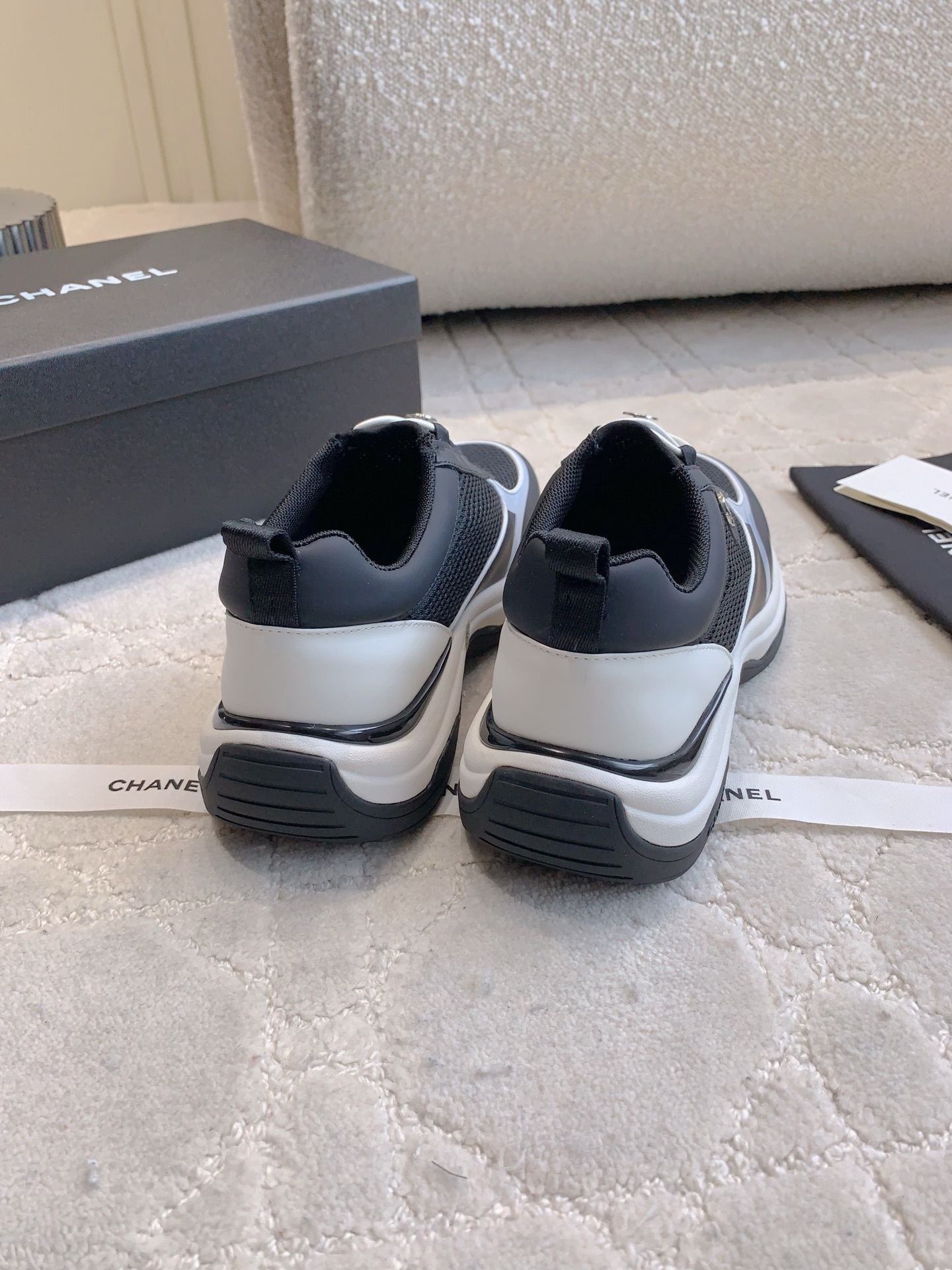 A pair of luxury Chanel black and white sneakers with mesh panels and CC logo on a white carpet. - Hình 8