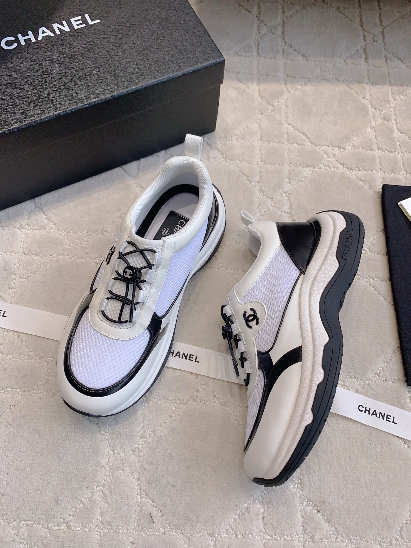 Chanel white and black mesh sneakers with CC logo and chunky sole displayed with original luxury packaging. - Hình 3