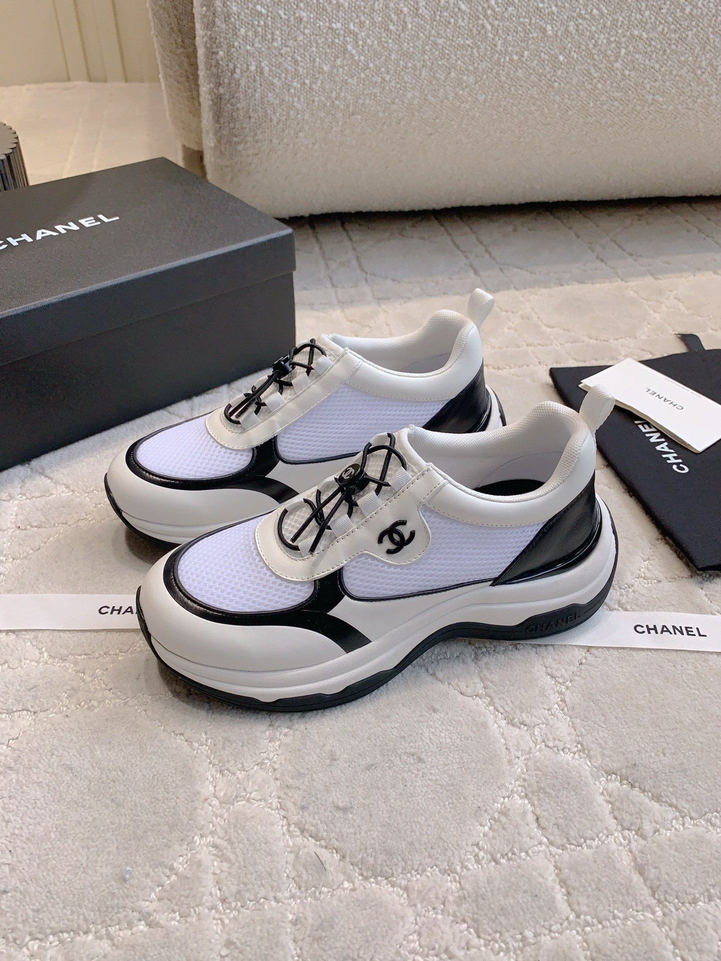 Chanel white and black mesh sneakers with CC logo and chunky sole displayed with original luxury packaging. - Hình 2