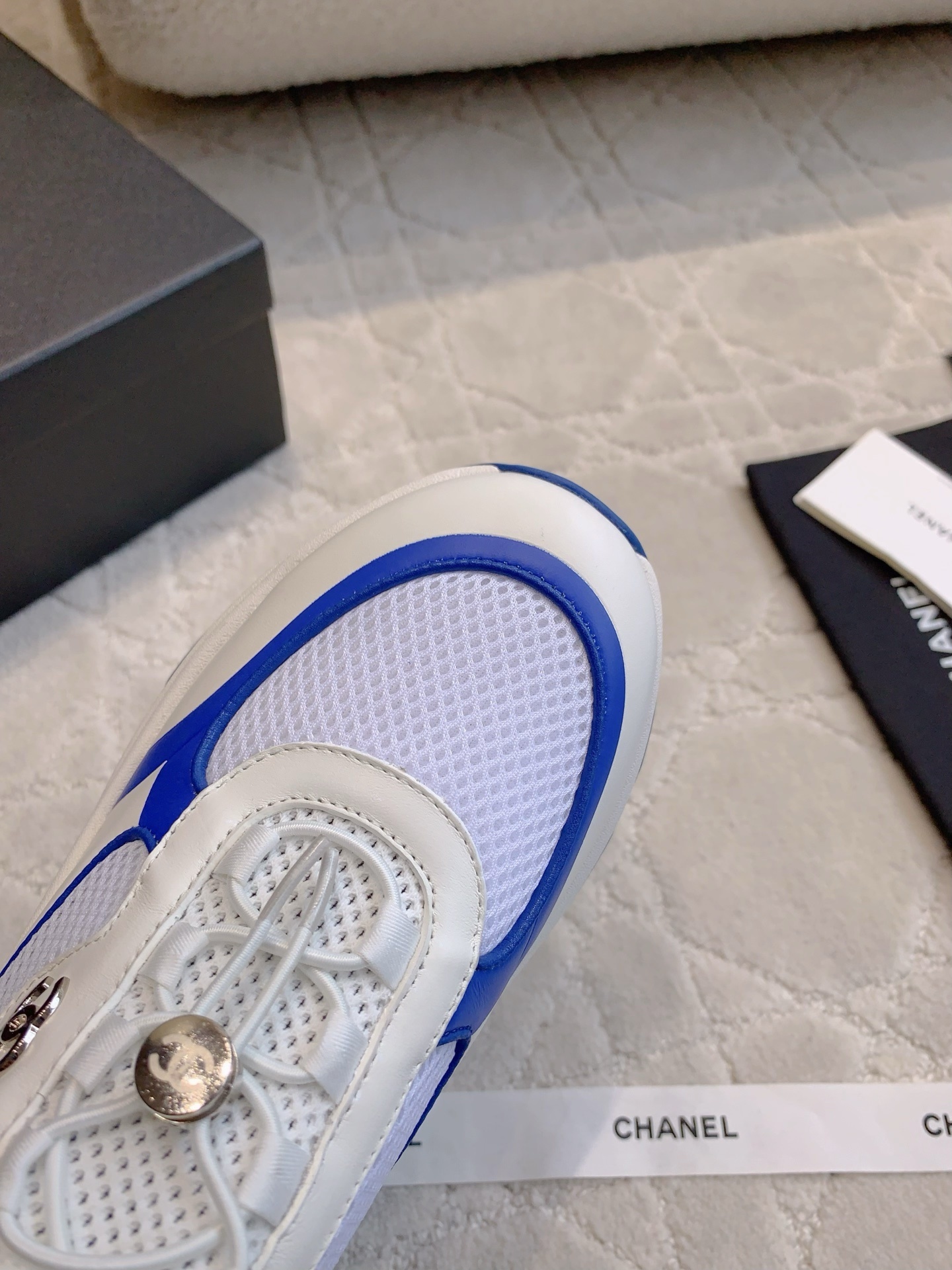 Chanel blue, white, and yellow mesh sneakers with CC logo toggle laces displayed with original packaging box and ribbons. - Hình 4