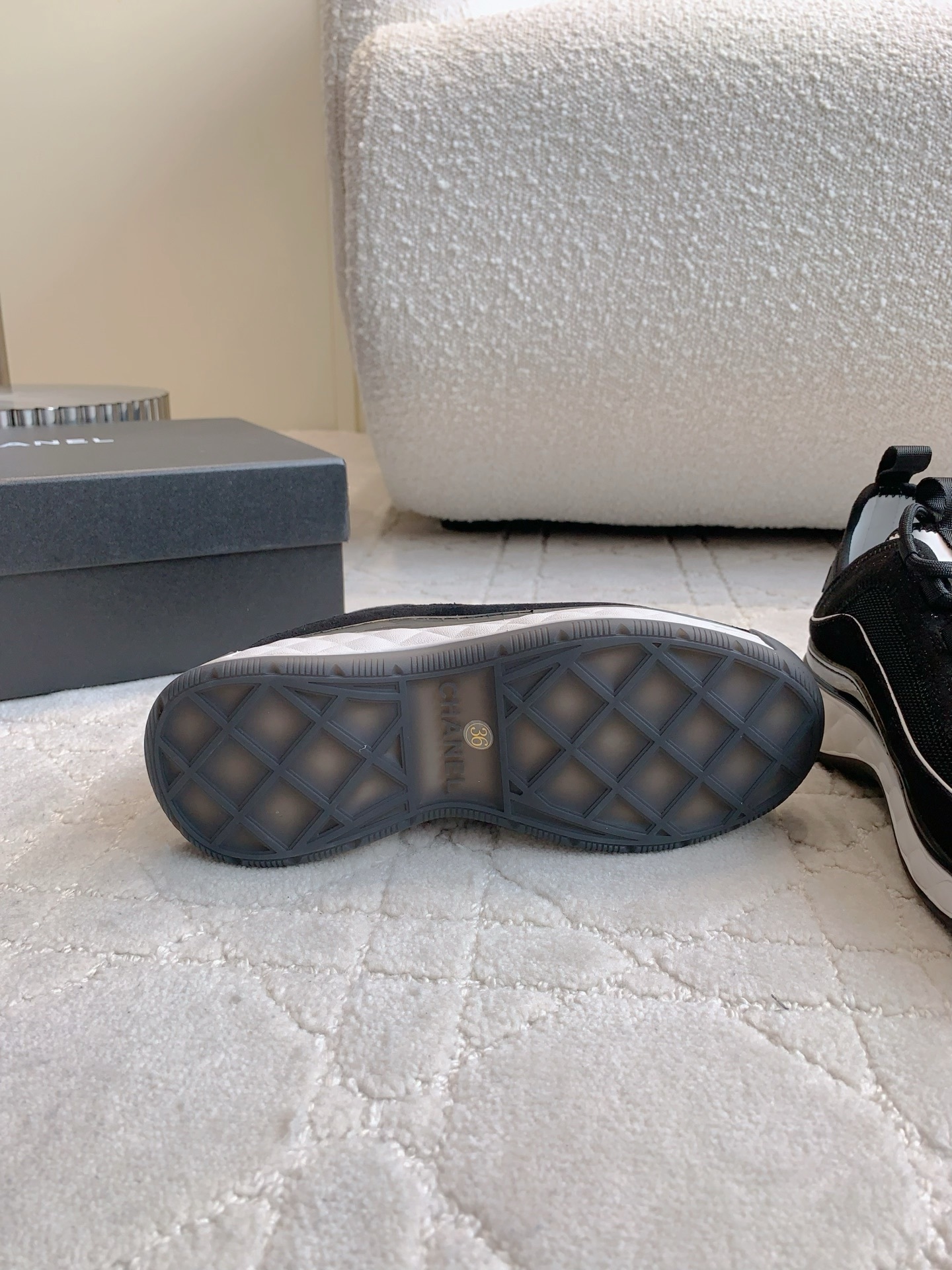 A pair of black Chanel mesh and suede sneakers with gold CC logo and white chunky soles displayed on a patterned carpet. - Hình 9