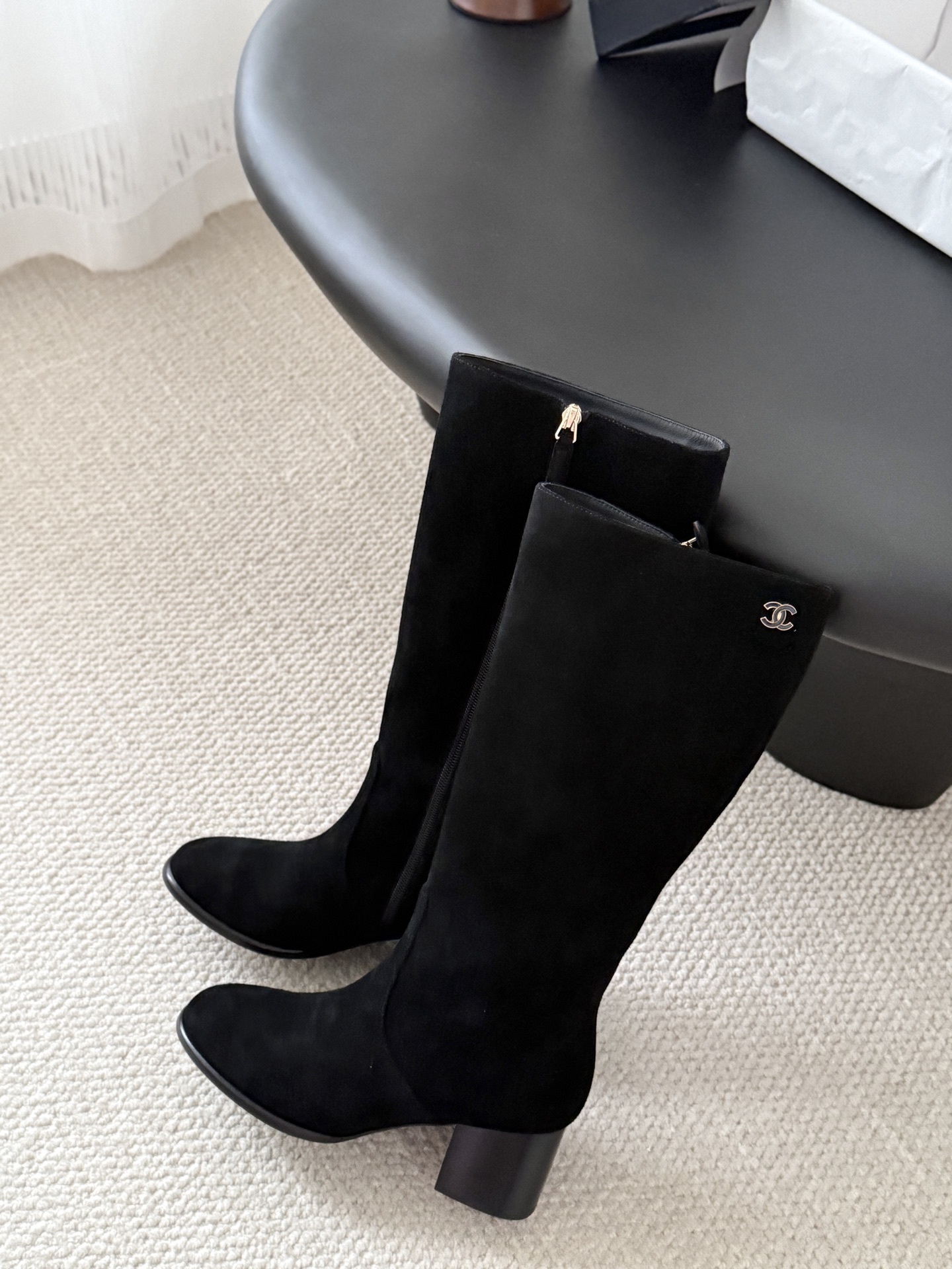 Pair of elegant black suede knee-high boots featuring a gold logo and a comfortable block heel. - Hình 8