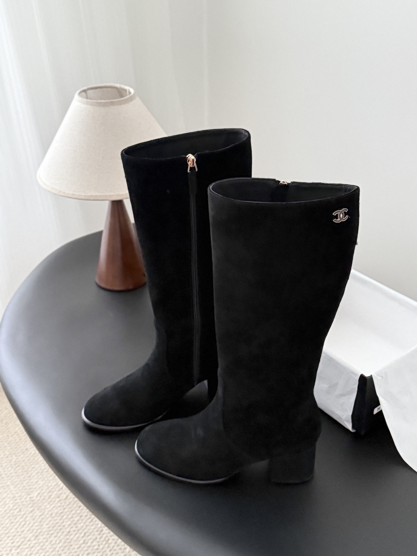 Pair of elegant black suede knee-high boots featuring a gold logo and a comfortable block heel. - Hình 6