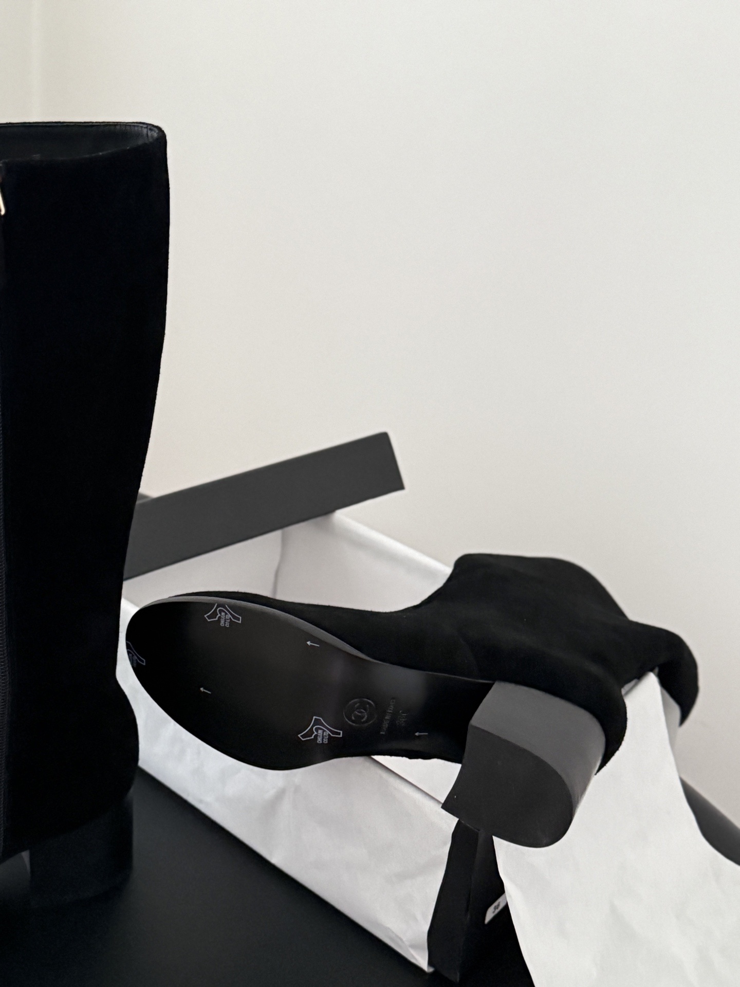 Pair of elegant black suede knee-high boots featuring a gold logo and a comfortable block heel. - Hình 5