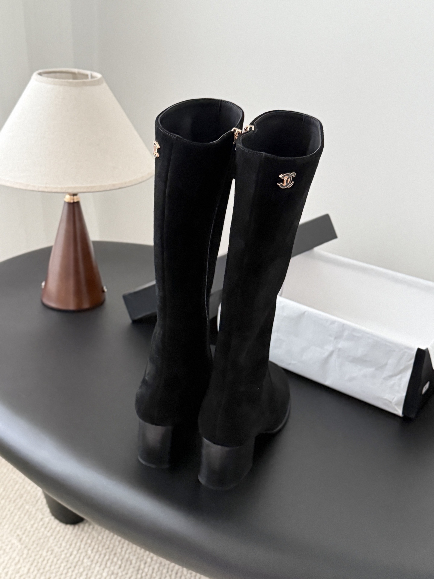 Pair of elegant black suede knee-high boots featuring a gold logo and a comfortable block heel. - Hình 3