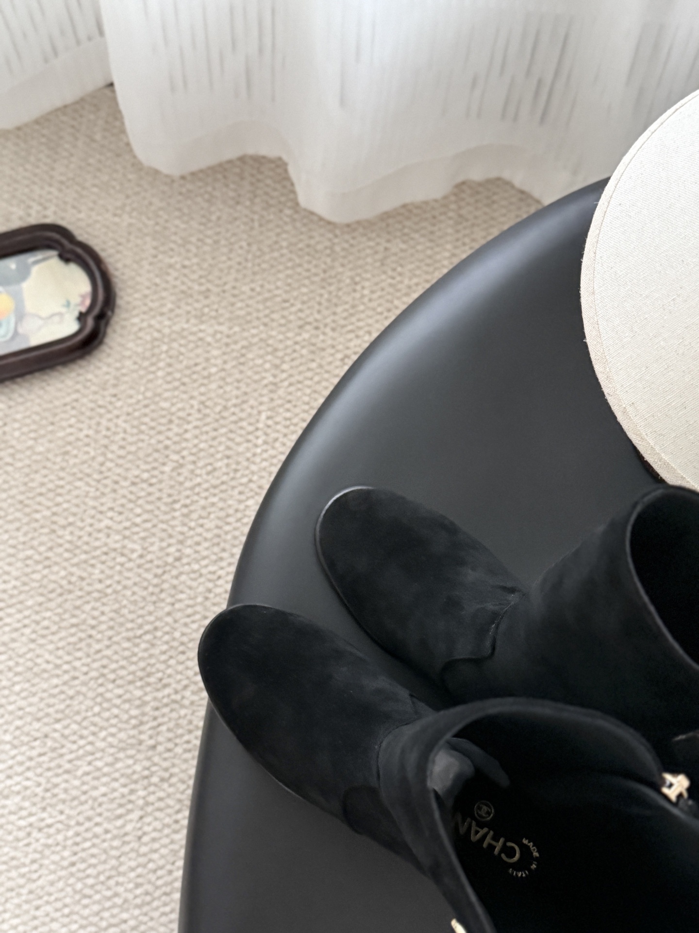 A pair of elegant black suede mid-calf boots with decorative gold logo buttons and a block heel, displayed next to a designer shoe box. - Hình 6