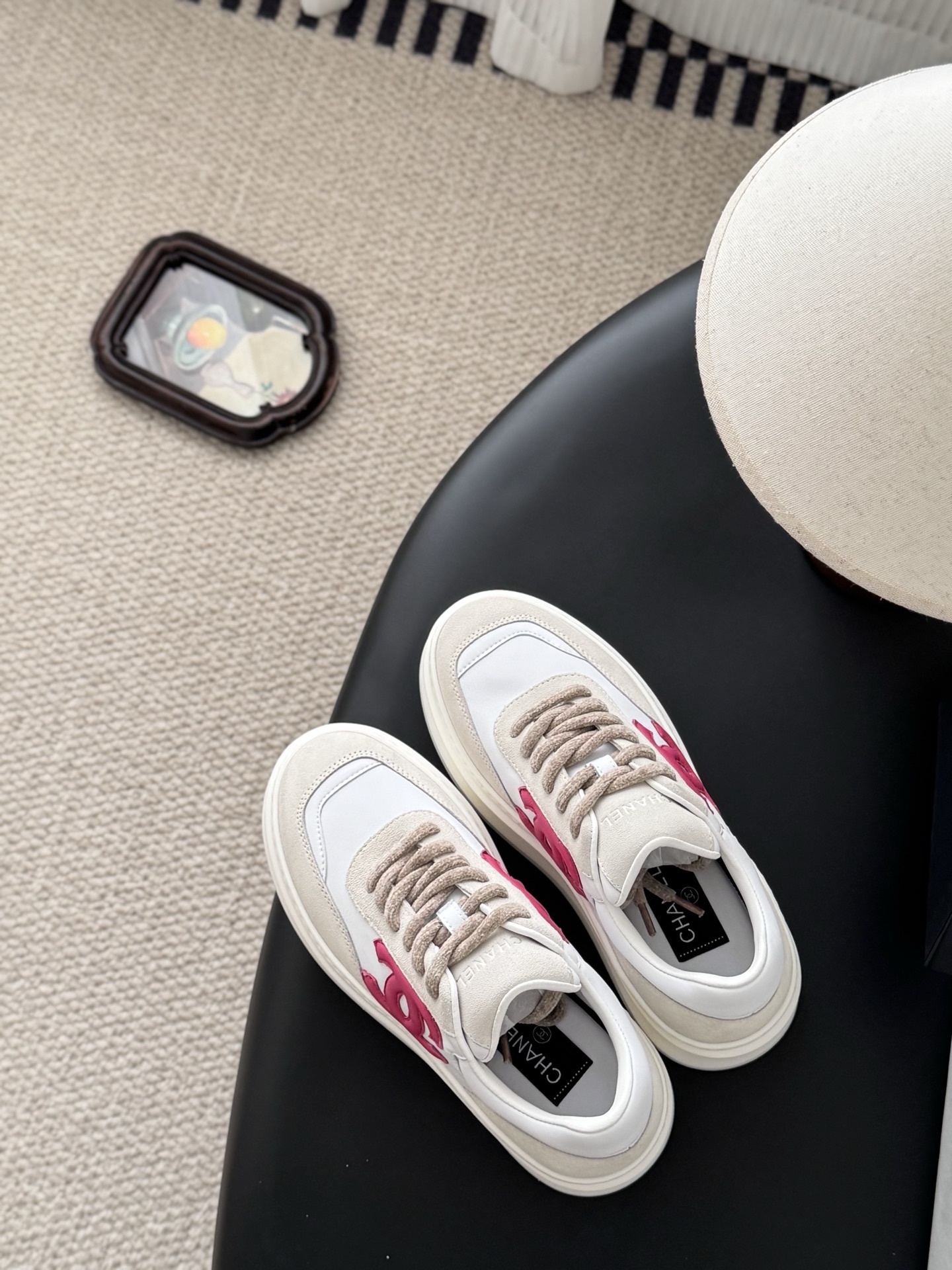 Pair of Chanel white and beige platform sneakers with pink CC logo next to a black Chanel shoe box - Hình 8