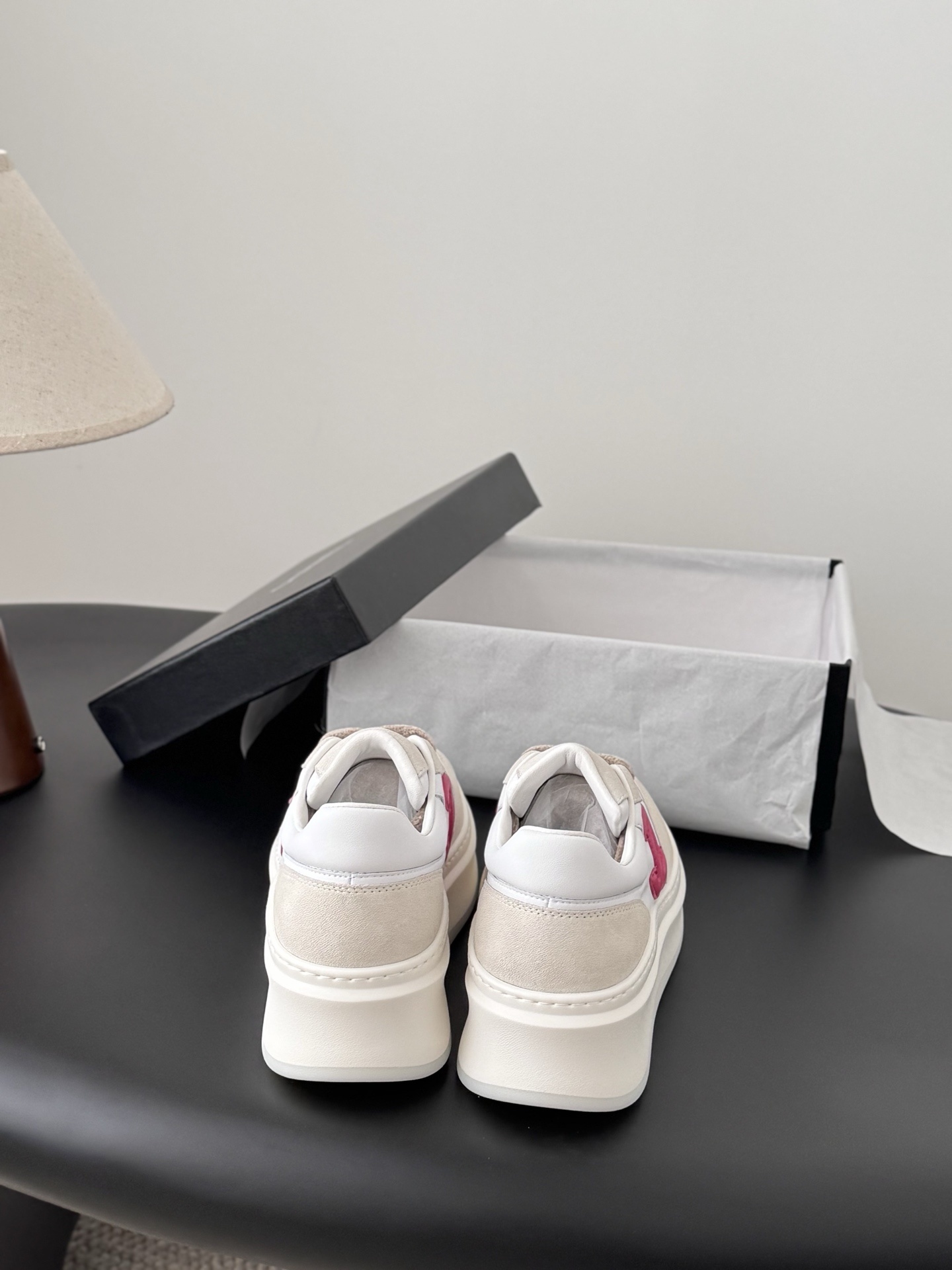 Pair of Chanel white and beige platform sneakers with pink CC logo next to a black Chanel shoe box - Hình 7