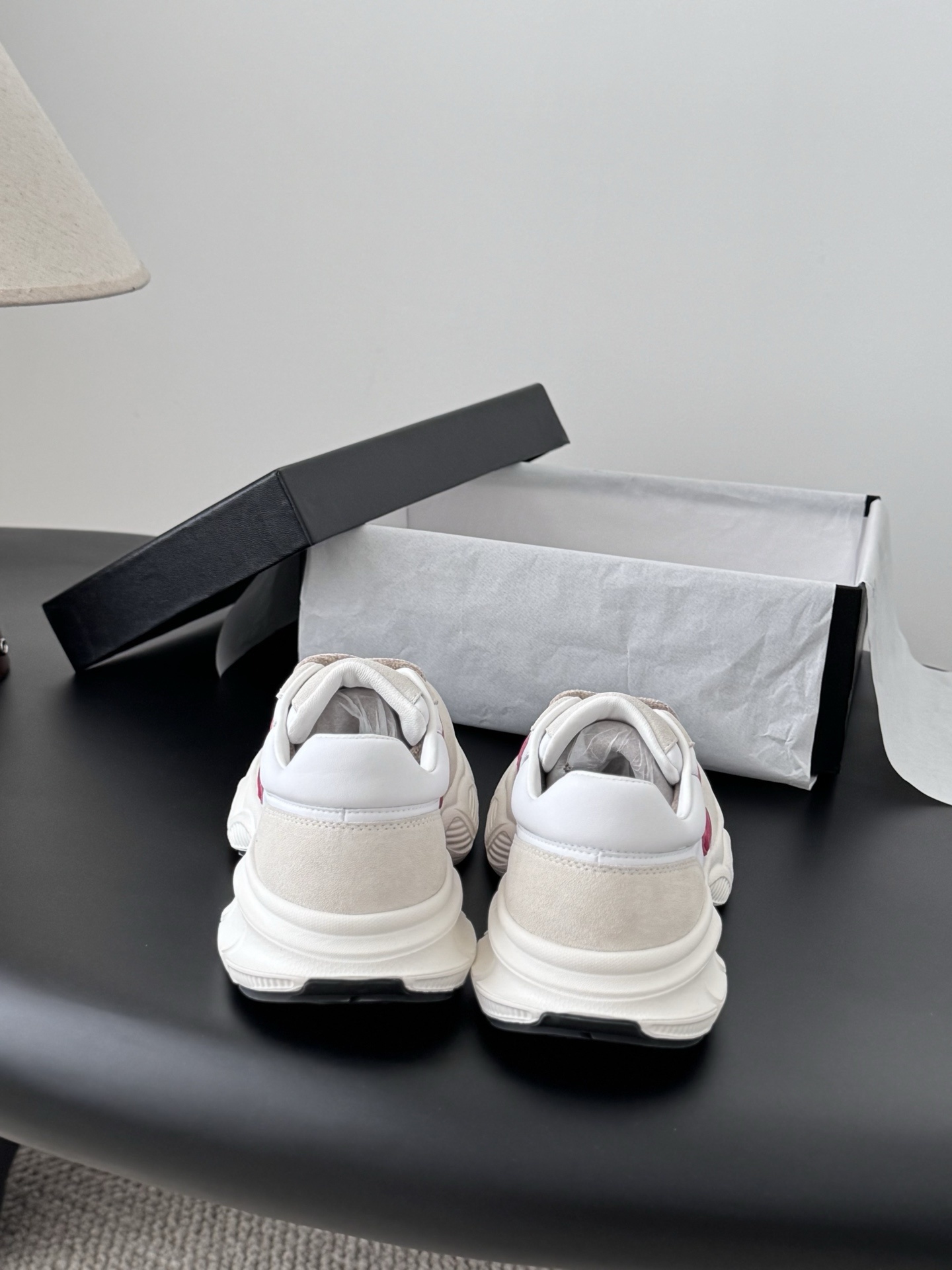 Pair of Chanel white leather and suede sneakers with pink interlocking CC logos next to a black Chanel box - Hình 7