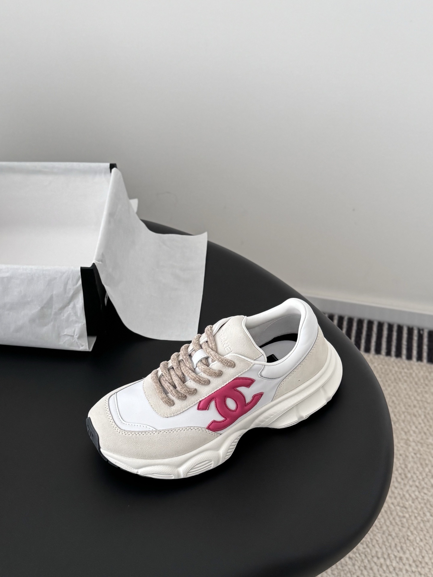 Pair of Chanel white leather and suede sneakers with pink interlocking CC logos next to a black Chanel box - Hình 5