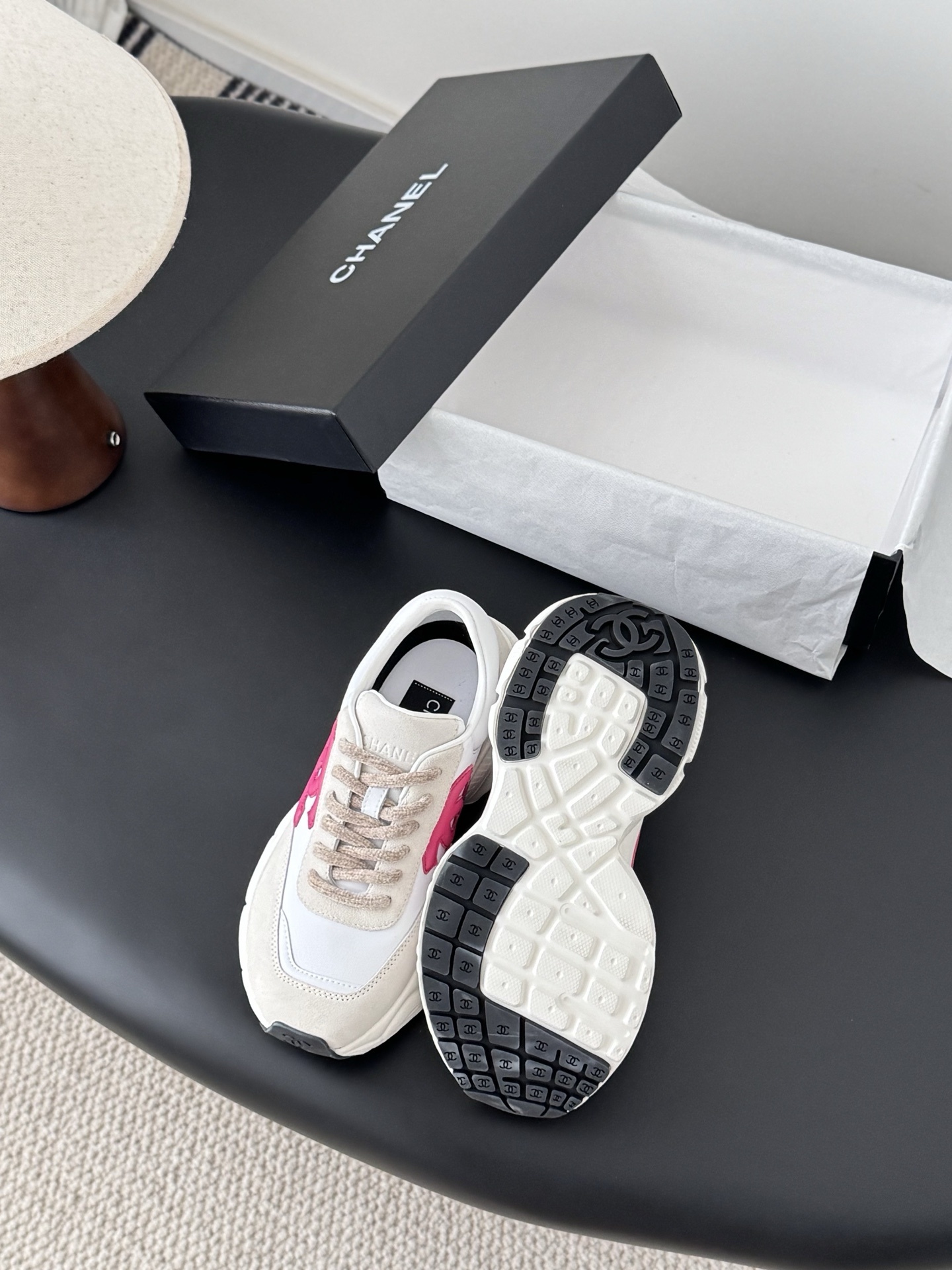 Pair of Chanel white leather and suede sneakers with pink interlocking CC logos next to a black Chanel box - Hình 4