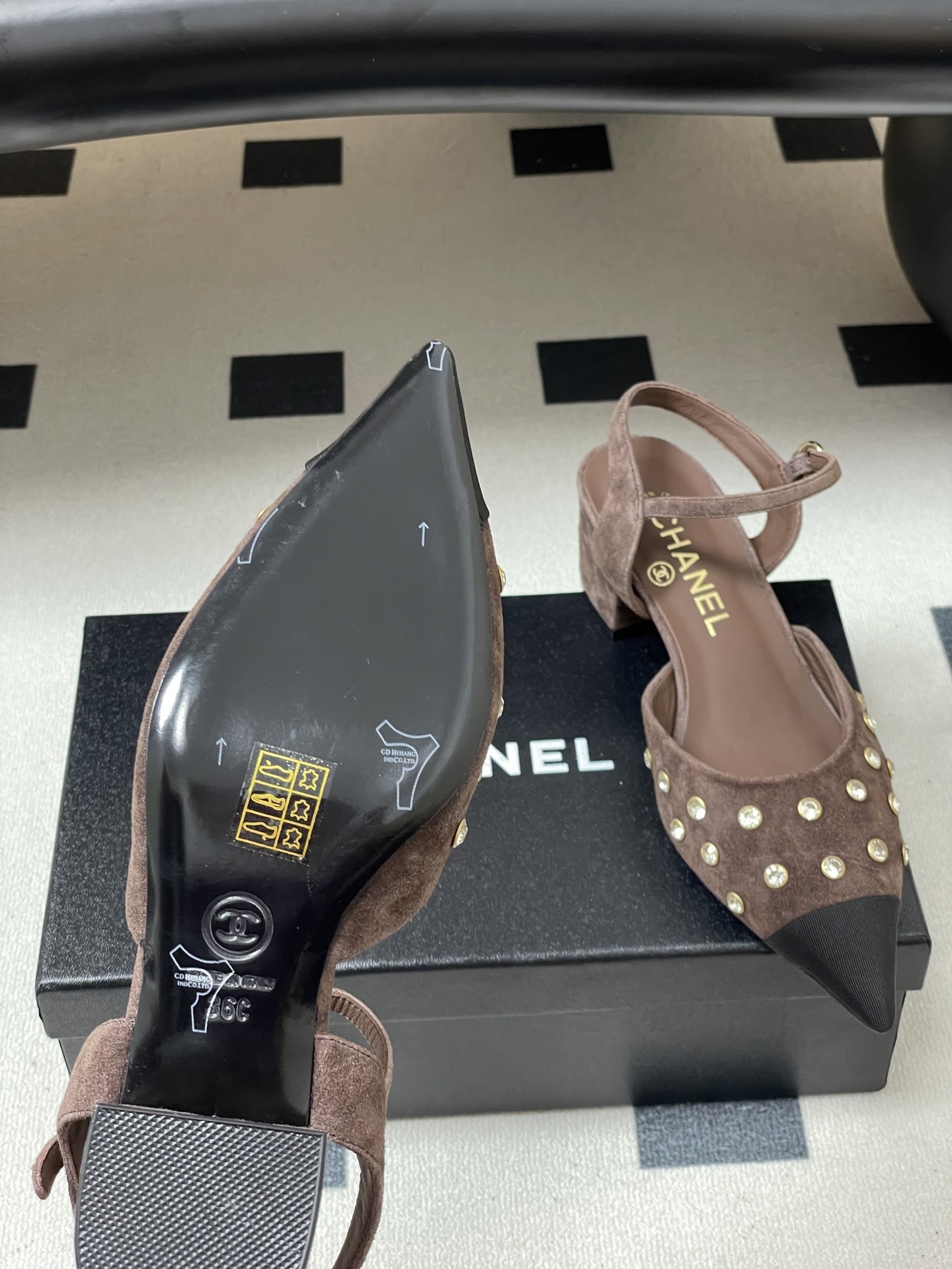 A pair of Chanel brown suede slingback pumps with crystal embellishments and black pointed toes on a black surface. - Hình 8