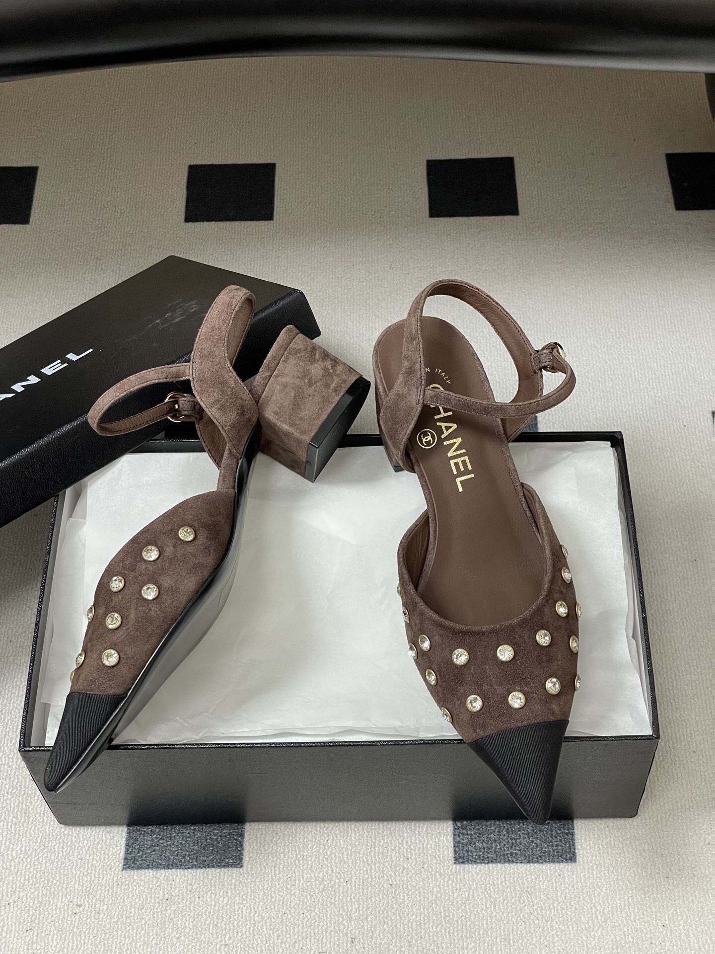 A pair of Chanel brown suede slingback pumps with crystal embellishments and black pointed toes on a black surface. - Hình 6