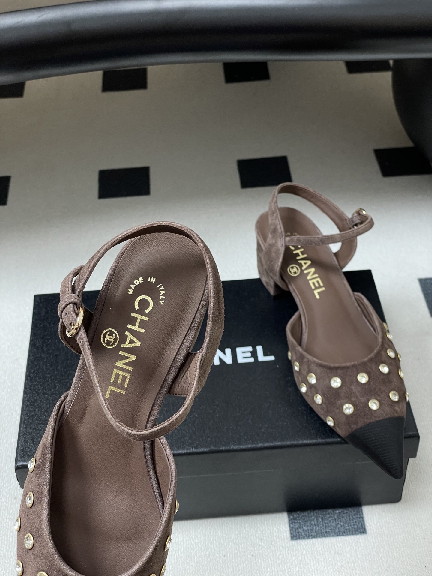 A pair of Chanel brown suede slingback pumps with crystal embellishments and black pointed toes on a black surface. - Hình 5