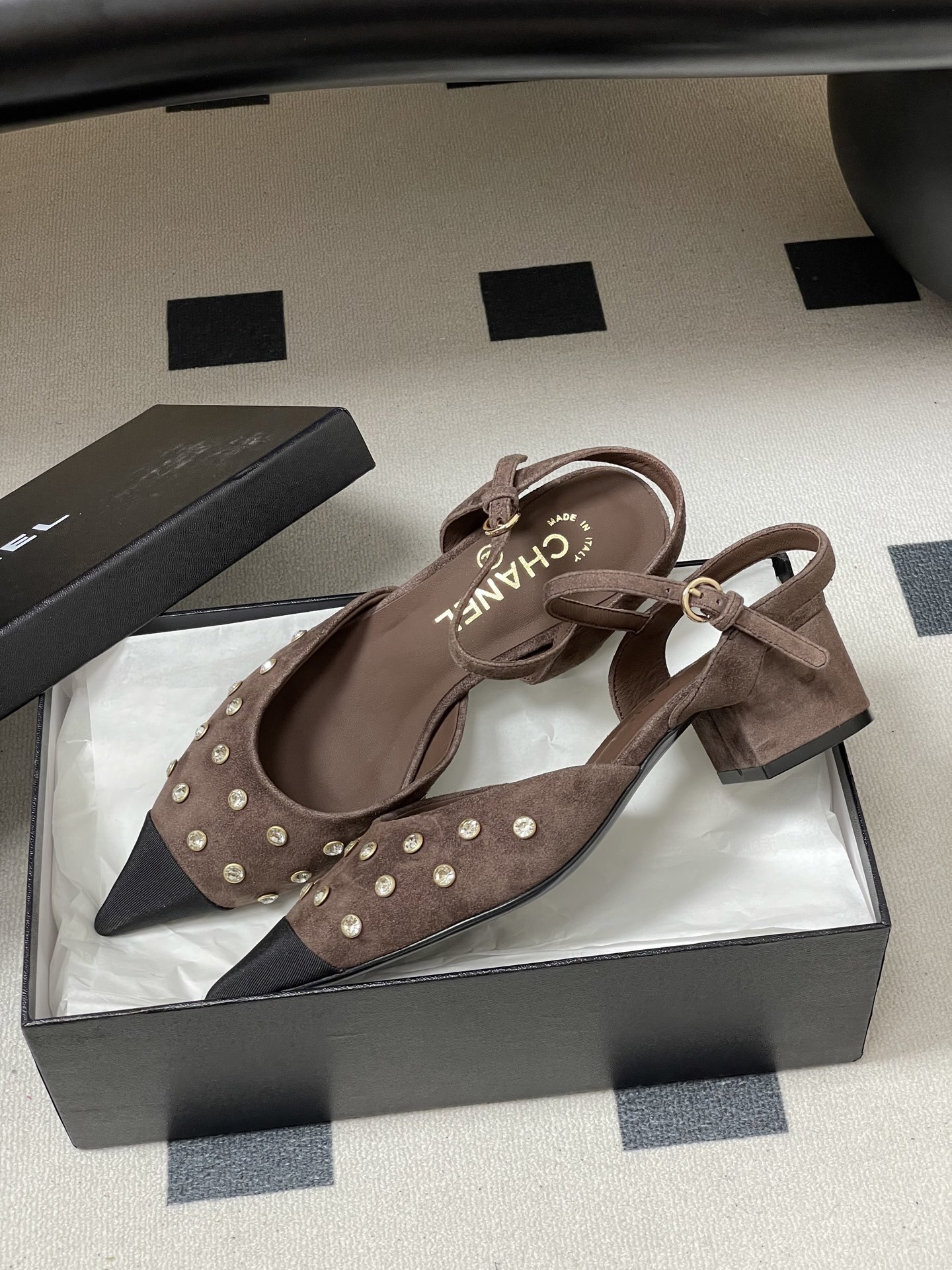 A pair of Chanel brown suede slingback pumps with crystal embellishments and black pointed toes on a black surface. - Hình 4