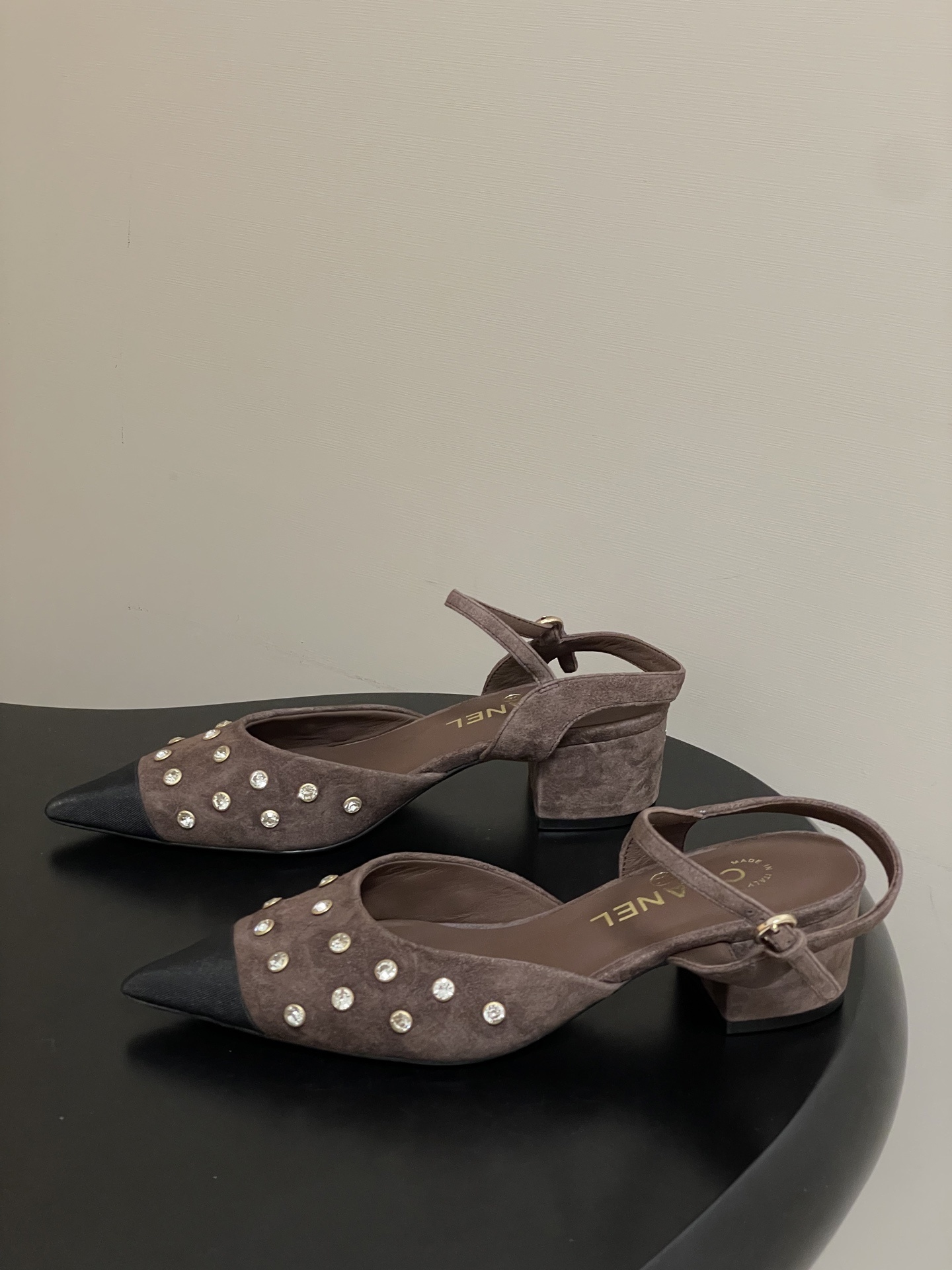 A pair of Chanel brown suede slingback pumps with crystal embellishments and black pointed toes on a black surface. - Hình 3