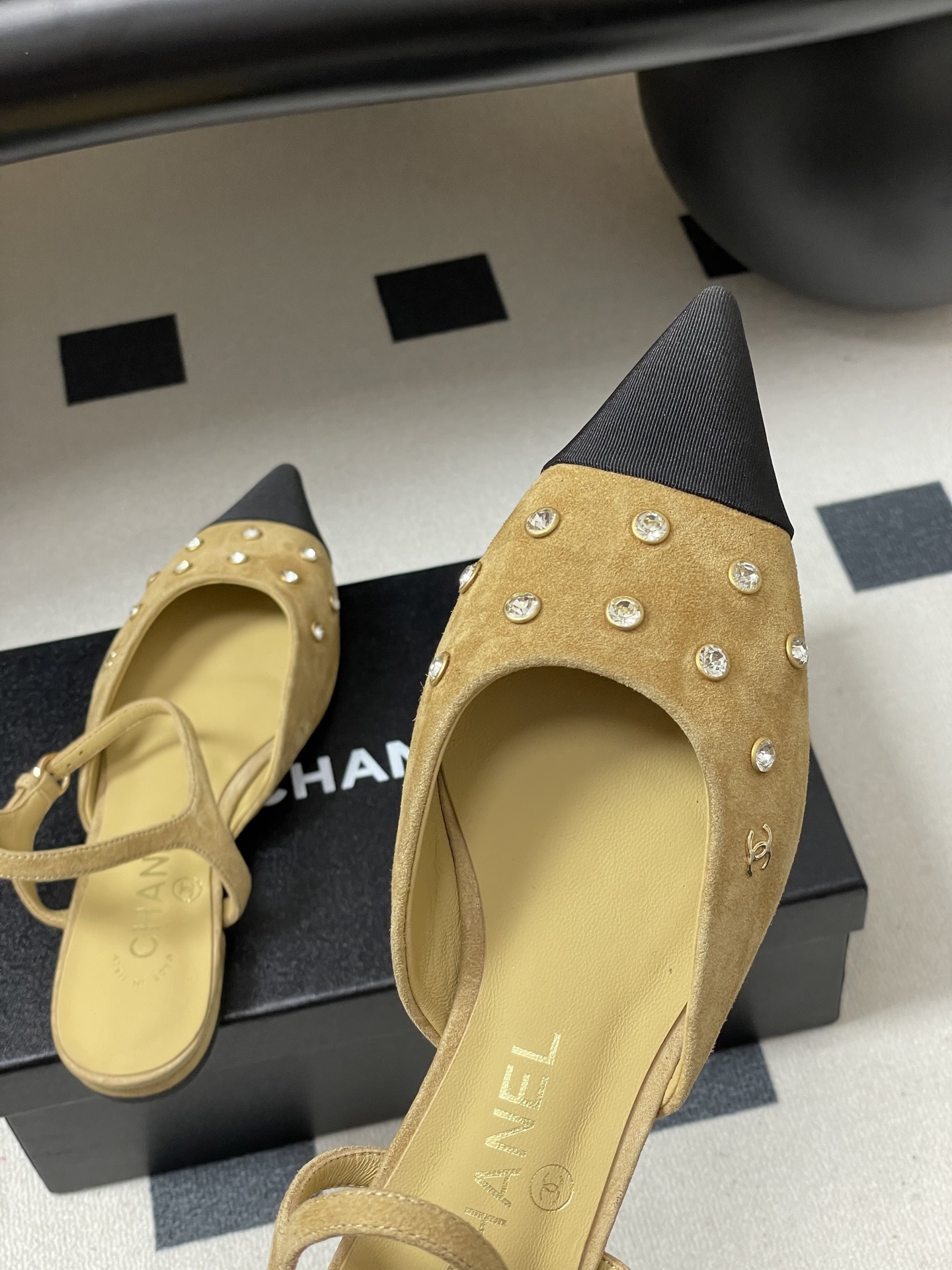 Luxury Chanel slingback flats in beige suede with crystal accents and black pointed toes on a black table. - Hình 9