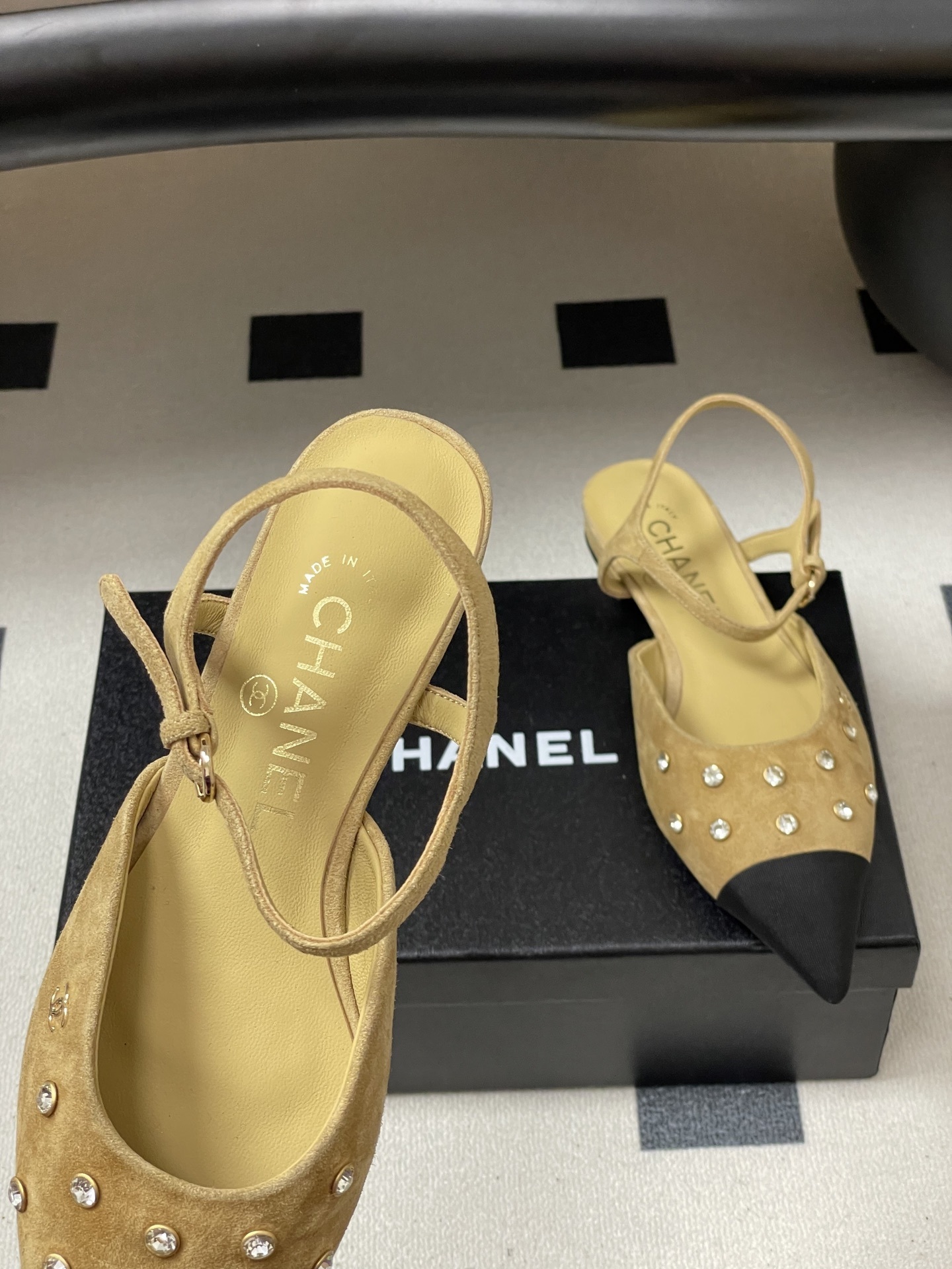 Luxury Chanel slingback flats in beige suede with crystal accents and black pointed toes on a black table. - Hình 7