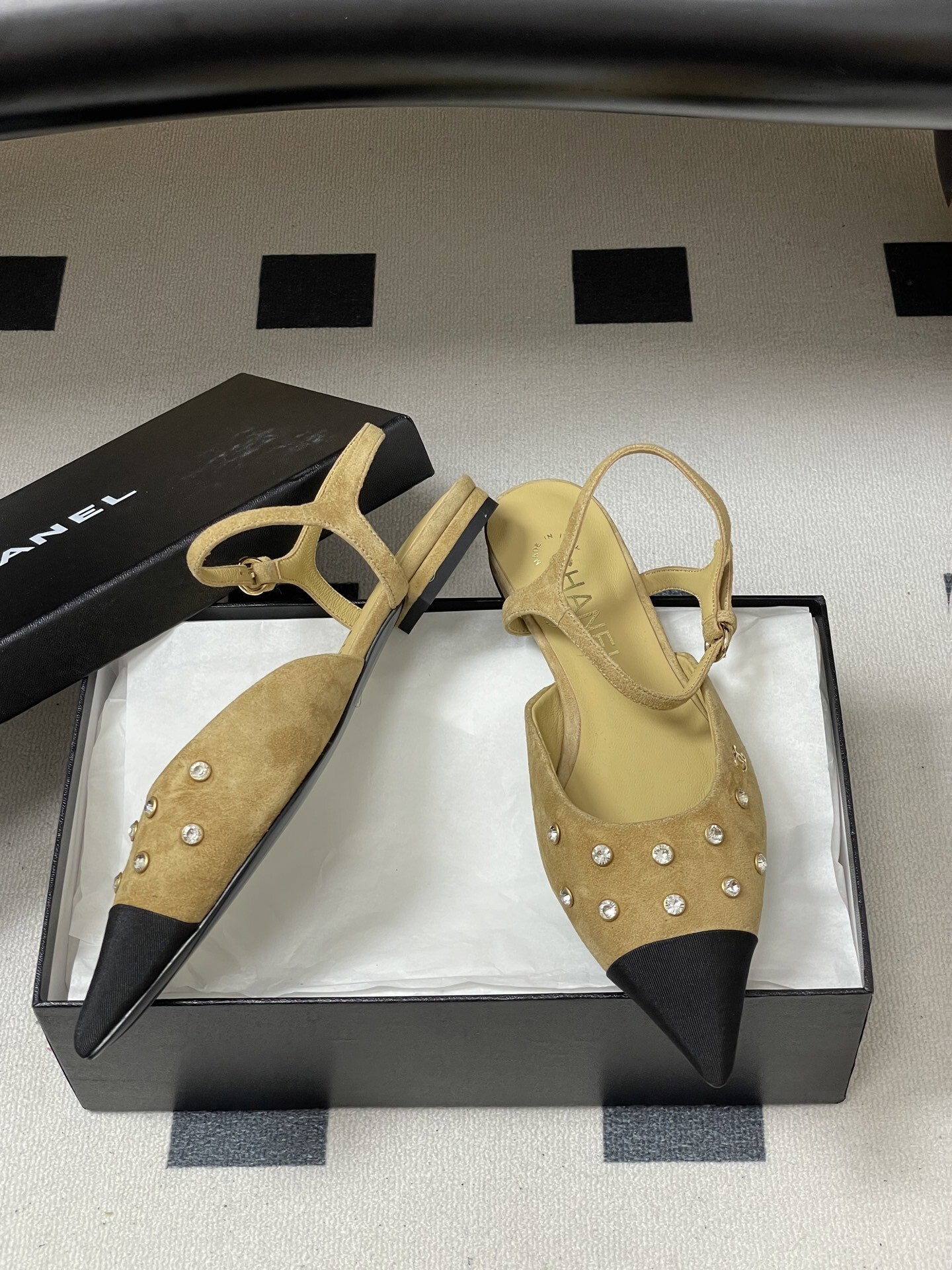 Luxury Chanel slingback flats in beige suede with crystal accents and black pointed toes on a black table. - Hình 6