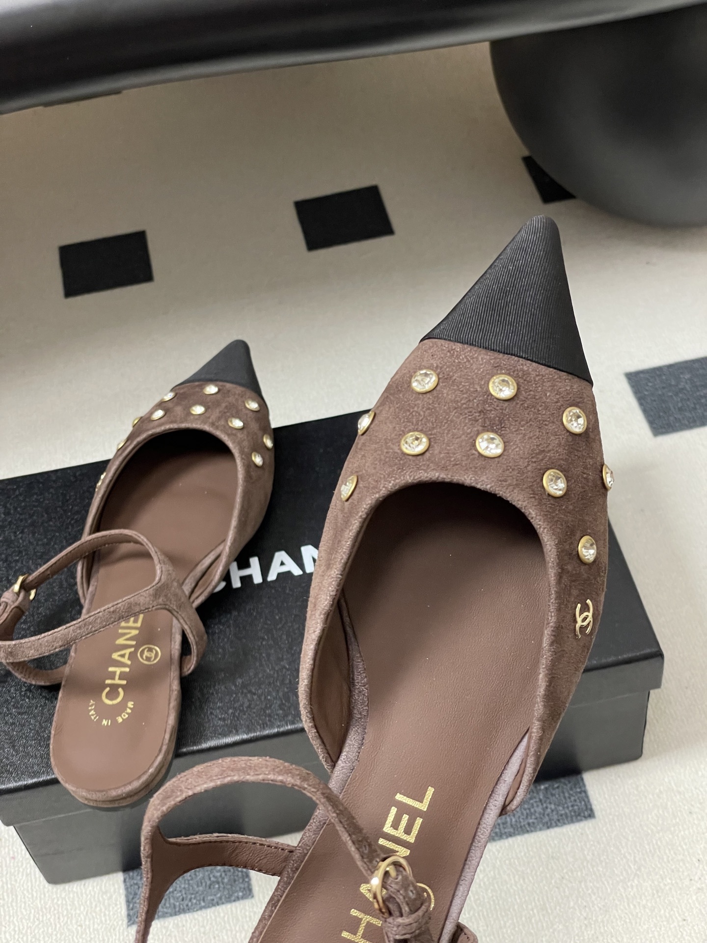 Pair of Chanel brown suede slingback flats with black pointed toes and crystal embellishments on a black table. - Hình 9