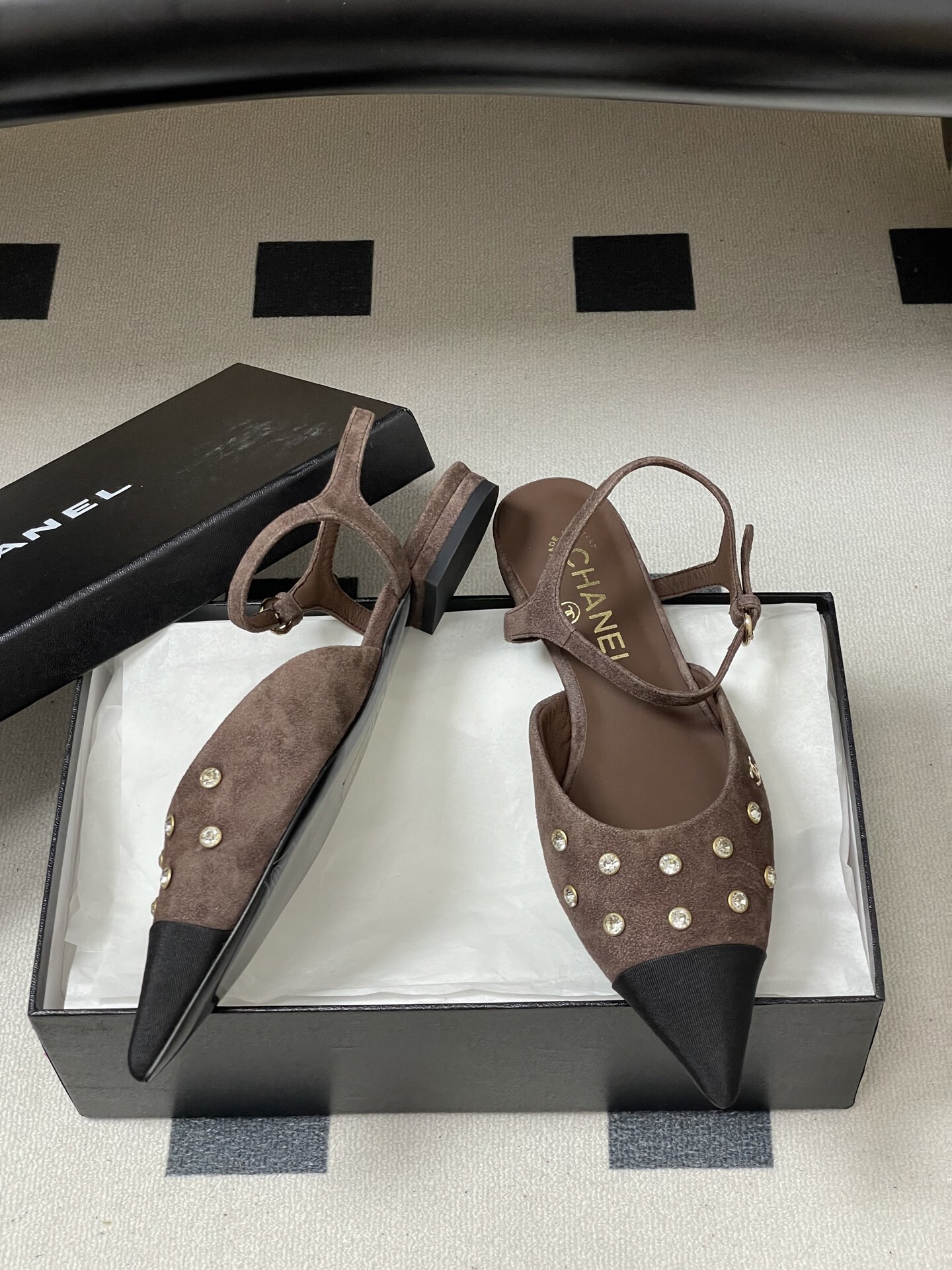 Pair of Chanel brown suede slingback flats with black pointed toes and crystal embellishments on a black table. - Hình 6