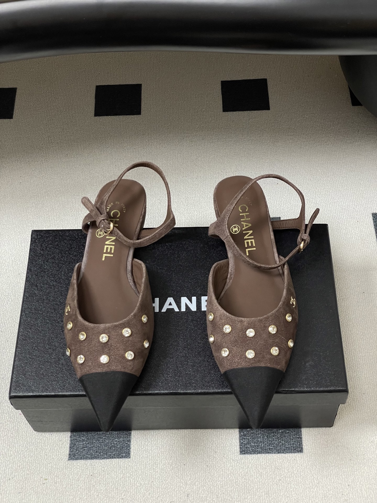 Pair of Chanel brown suede slingback flats with black pointed toes and crystal embellishments on a black table. - Hình 5