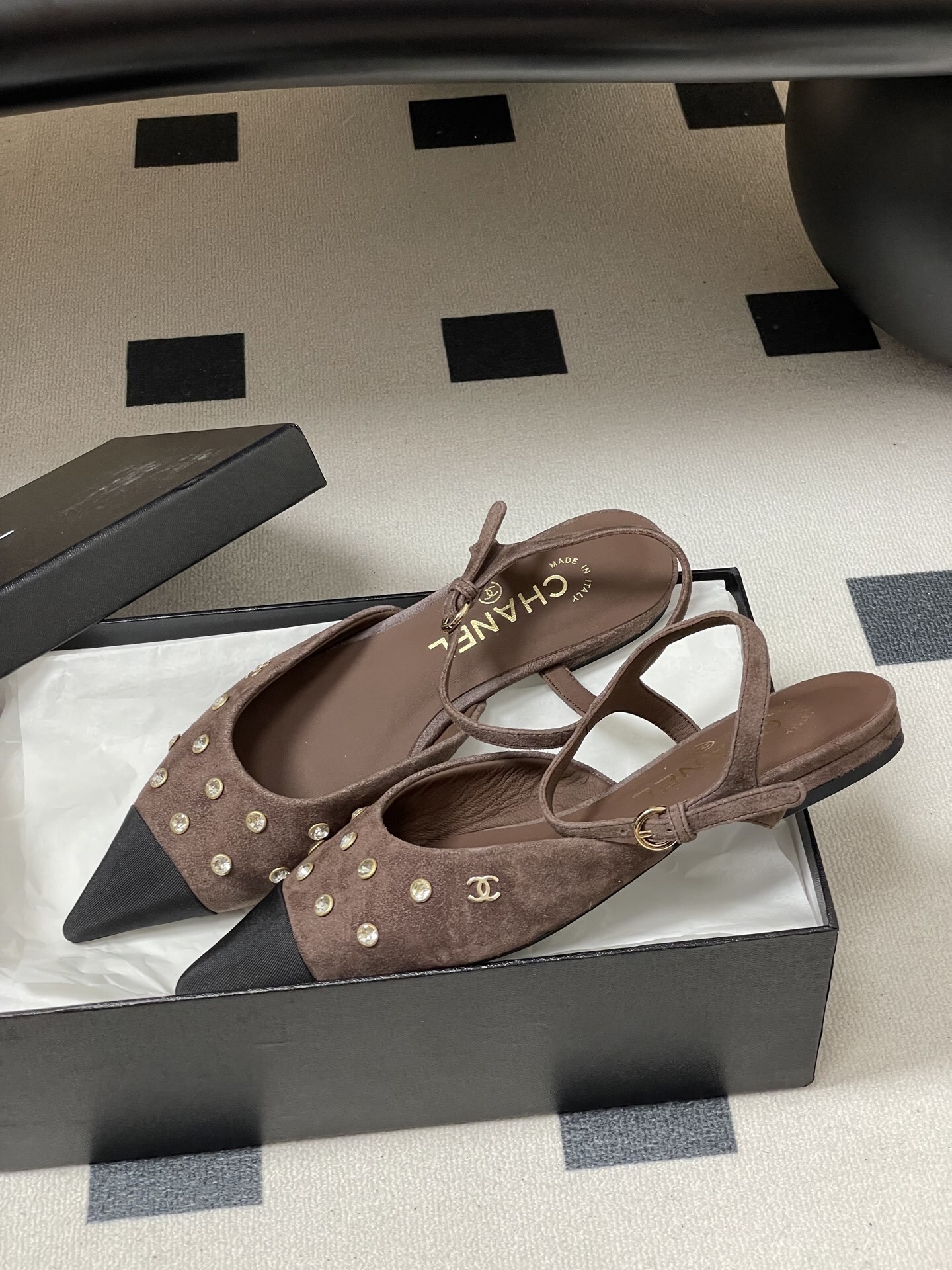 Pair of Chanel brown suede slingback flats with black pointed toes and crystal embellishments on a black table. - Hình 4