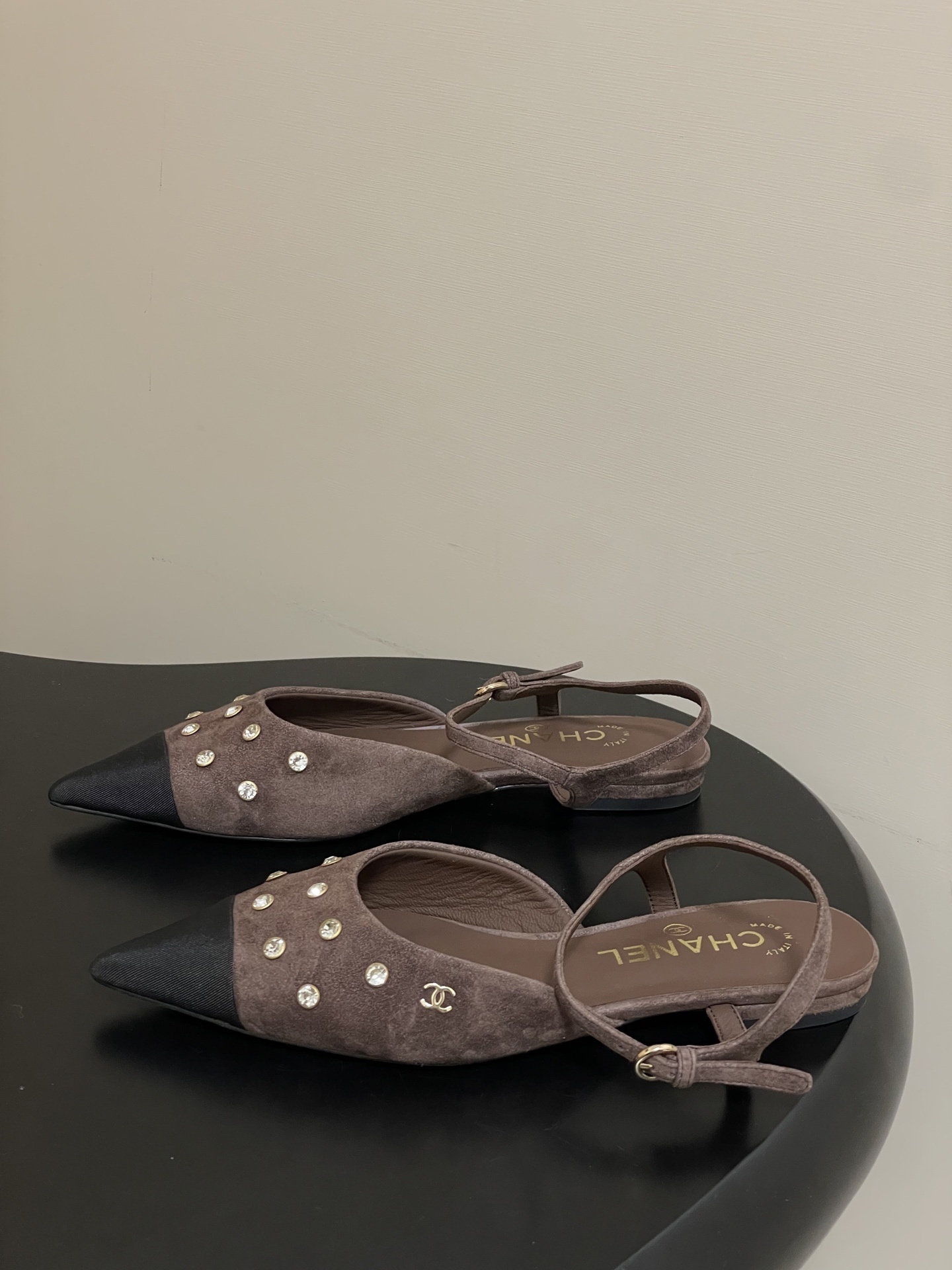 Pair of Chanel brown suede slingback flats with black pointed toes and crystal embellishments on a black table. - Hình 3
