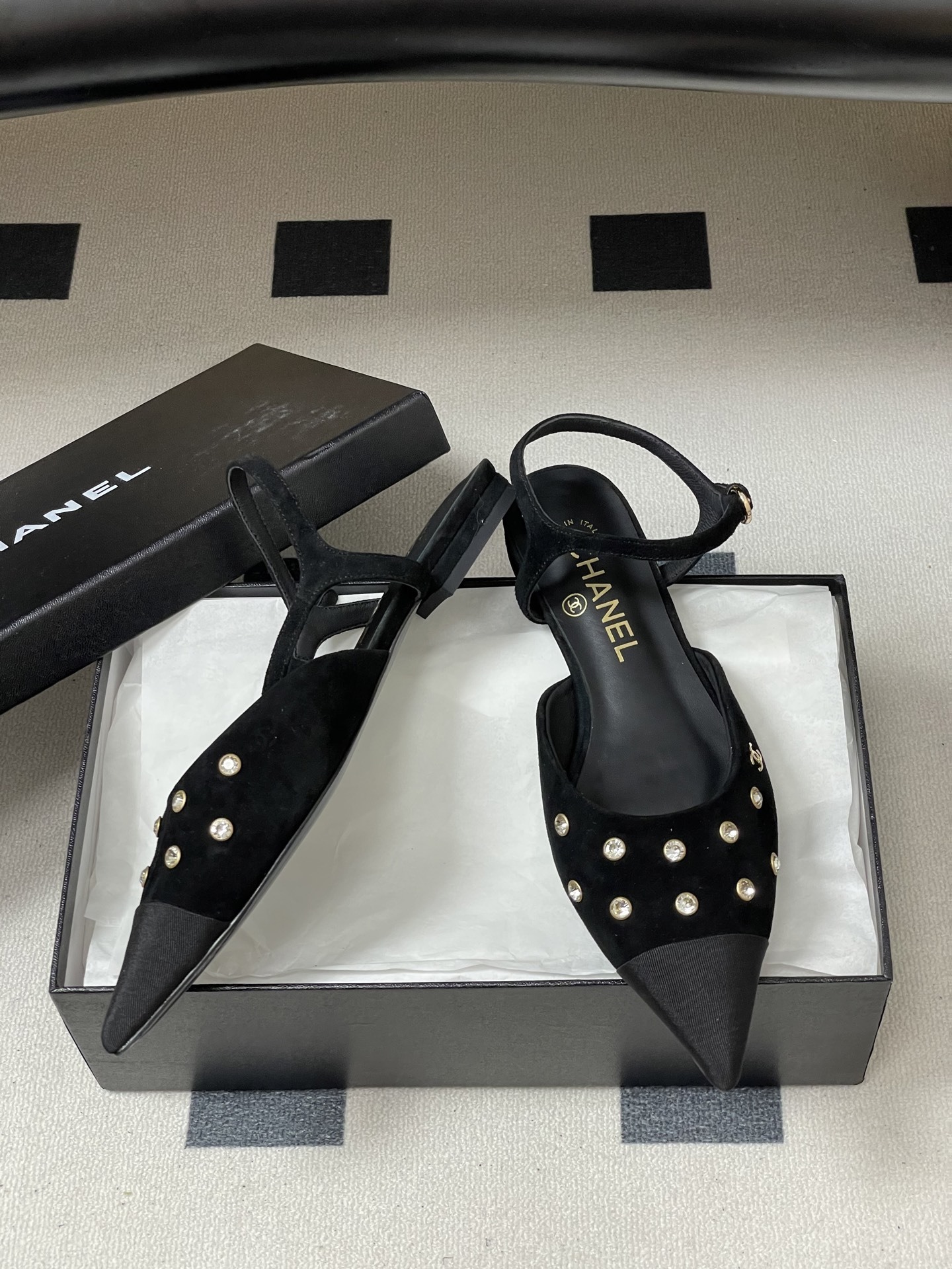 Chanel black suede pointed-toe slingback flats with crystal embellishments and gold CC logo on a black surface - Hình 6