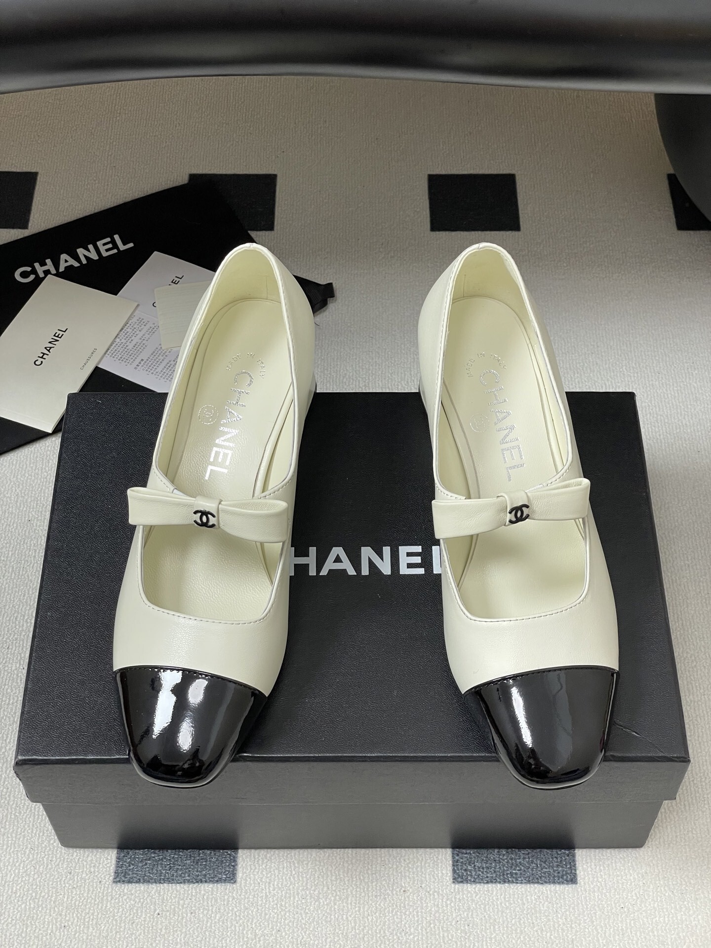 A pair of white leather Mary Jane block heels with black patent leather cap toes and decorative bows. - Hình 5