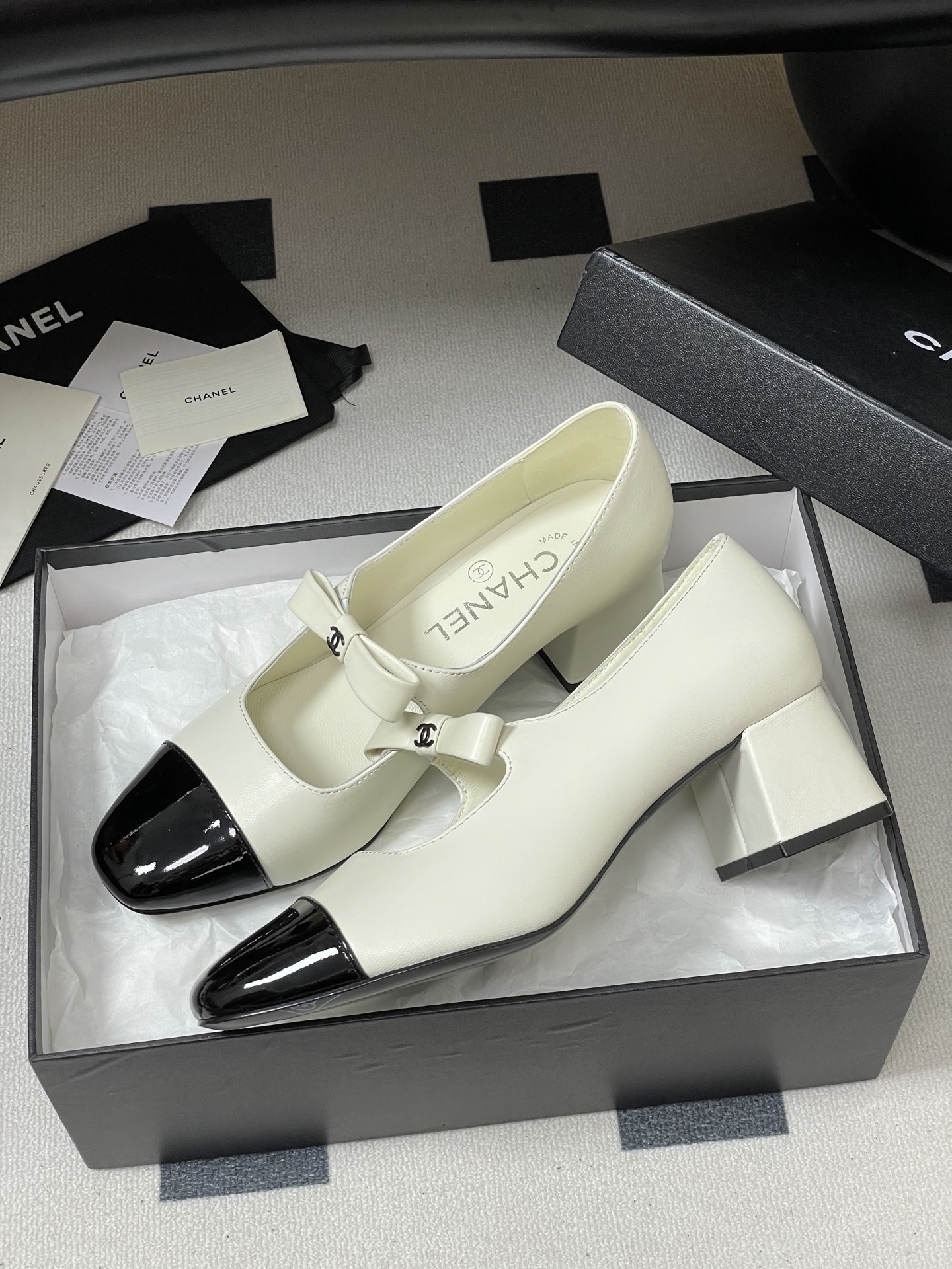 A pair of white leather Mary Jane block heels with black patent leather cap toes and decorative bows. - Hình 4