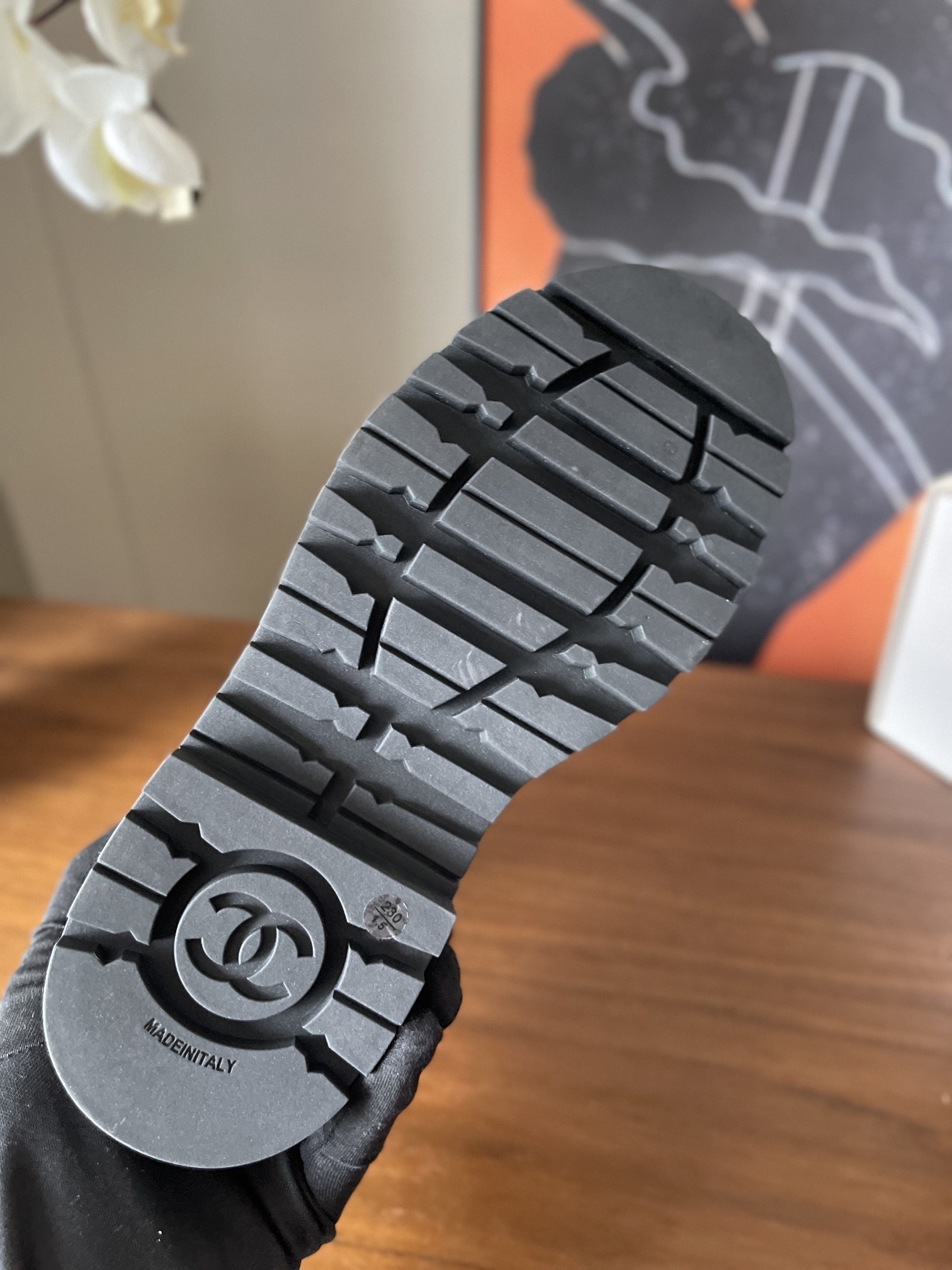 A pair of black Chanel quilted velvet combat boots with patent leather toe caps and gold lettering on a wooden surface. - Hình 8