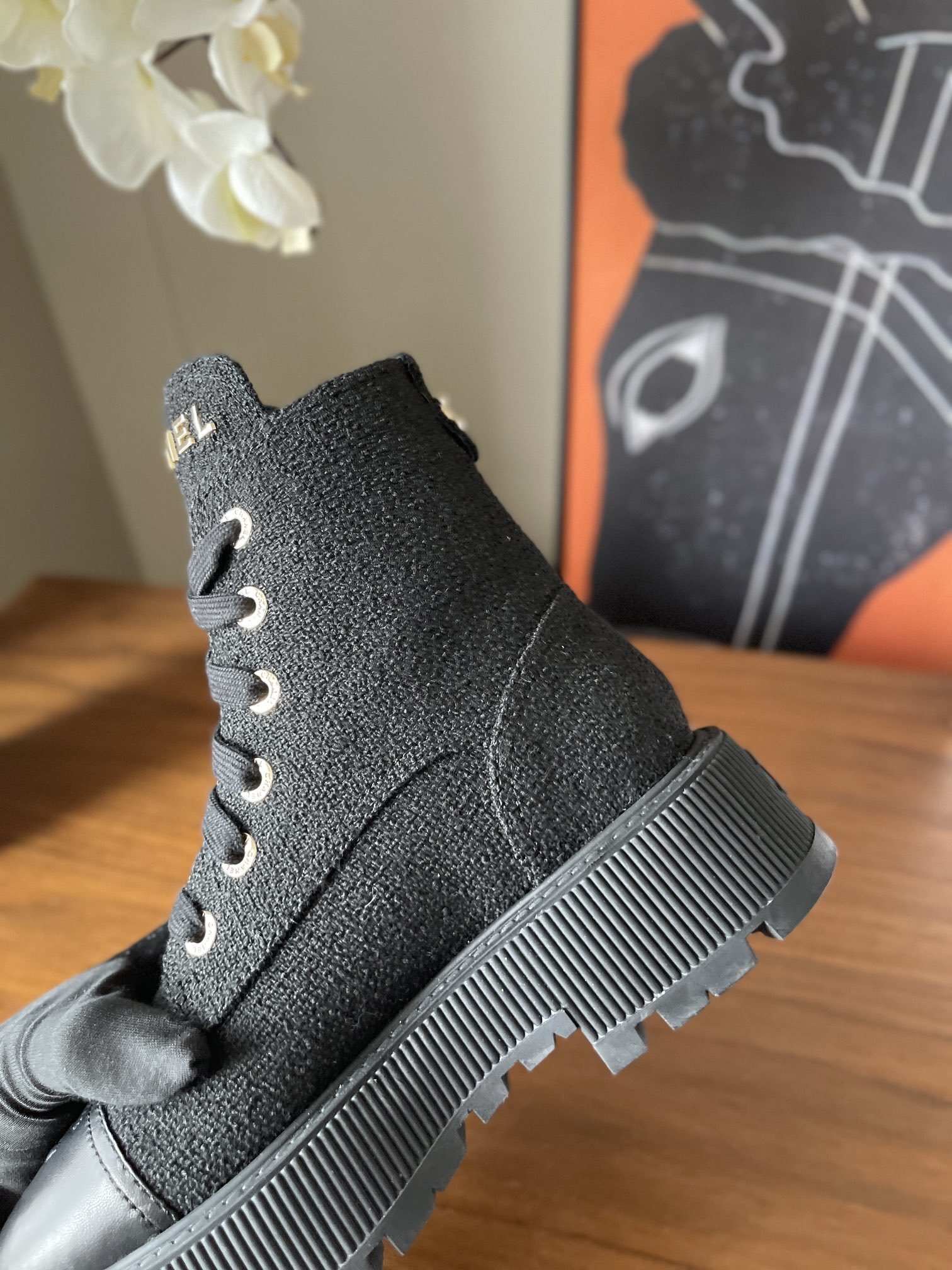 A pair of Chanel black tweed lace-up combat boots with gold lettering and chunky platform soles placed on a wooden surface. - Hình 7