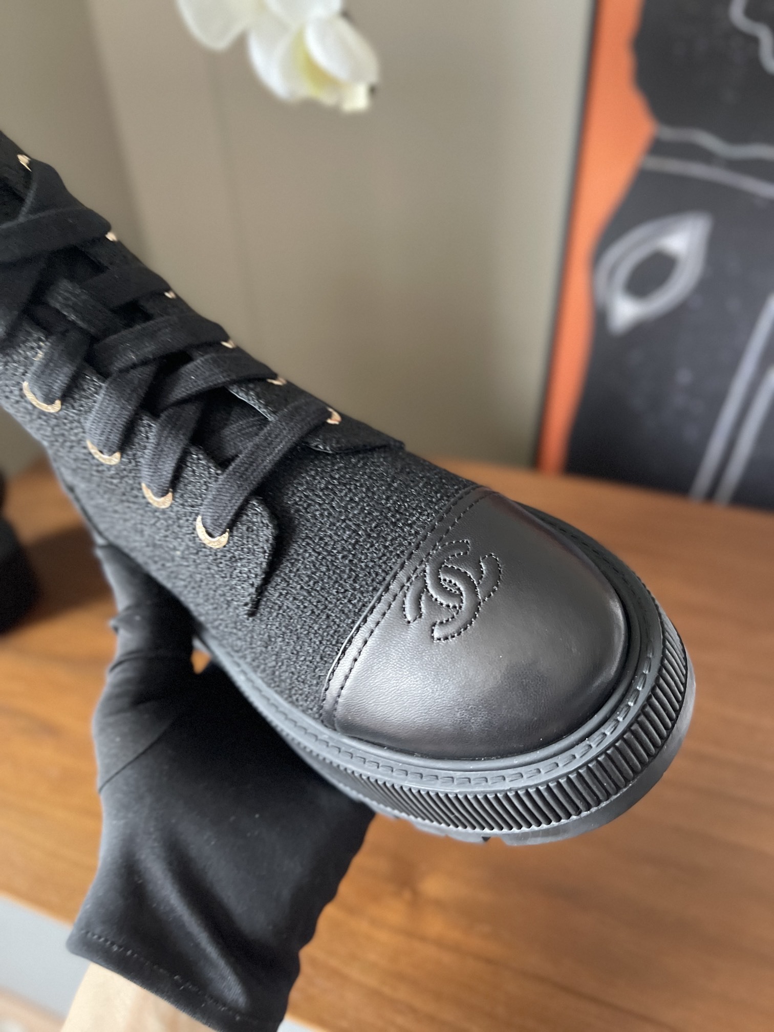 A pair of Chanel black tweed lace-up combat boots with gold lettering and chunky platform soles placed on a wooden surface. - Hình 6